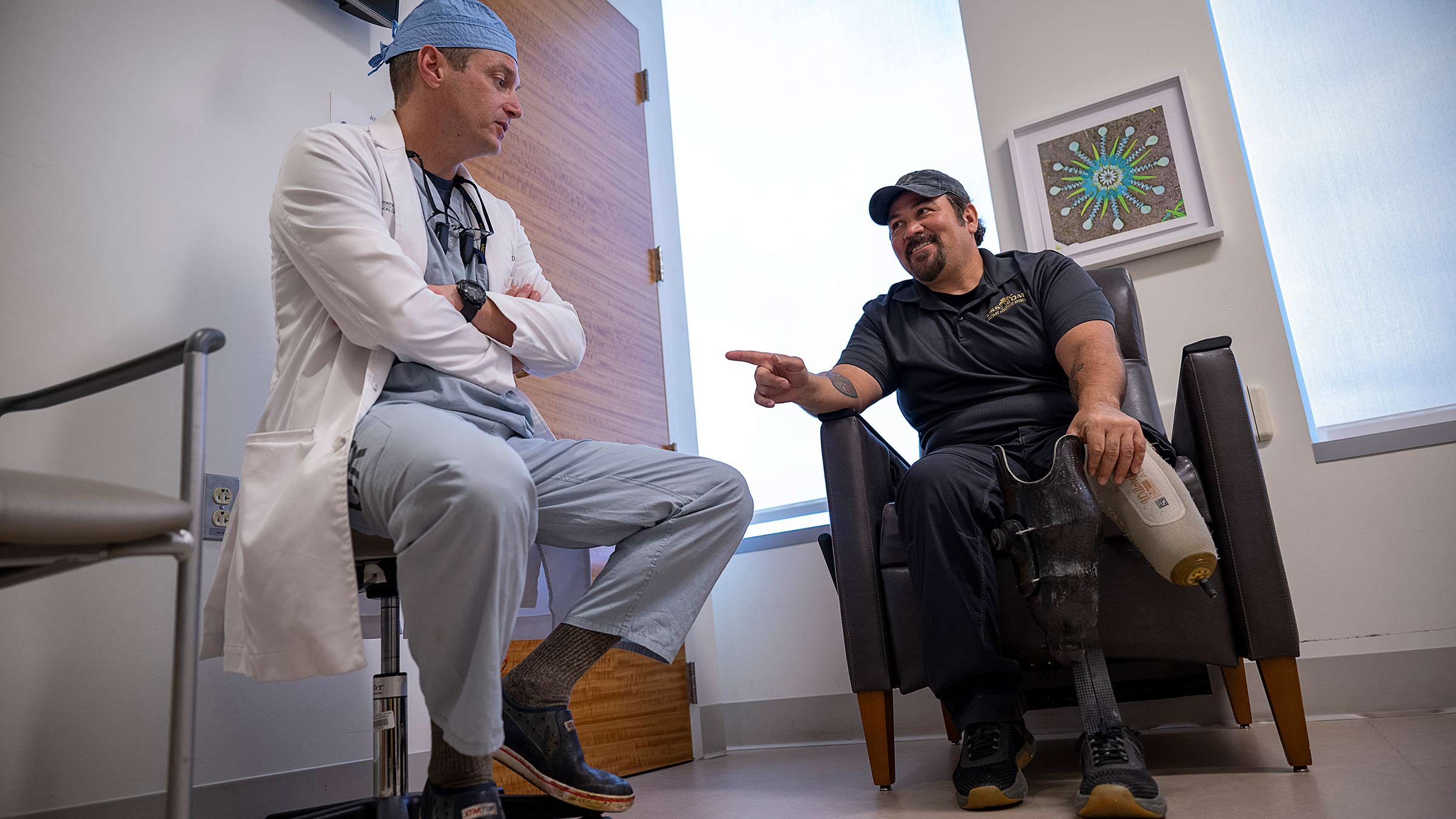 Jason Souza, MD, listening to a patient who is holding his prosthetic leg 