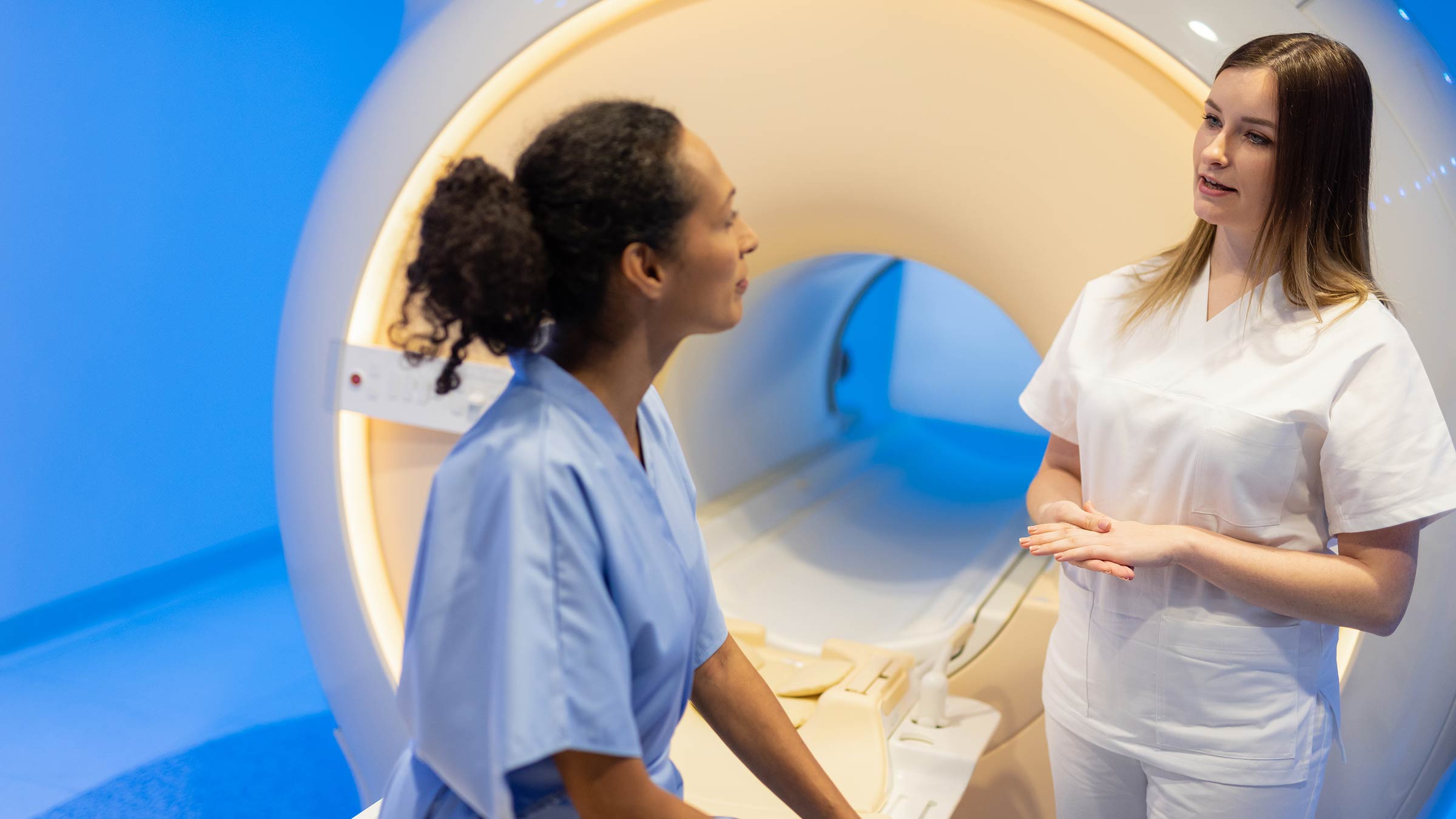 Female medical professional prepares a female patient for MRI scan