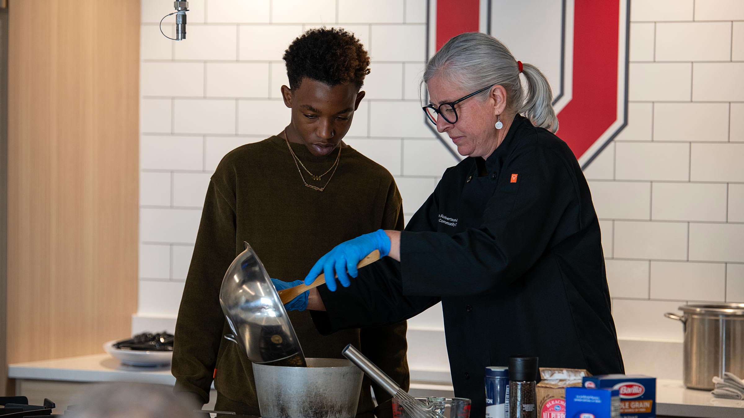 A woman teaching a young male a recipe in a kitchen setting