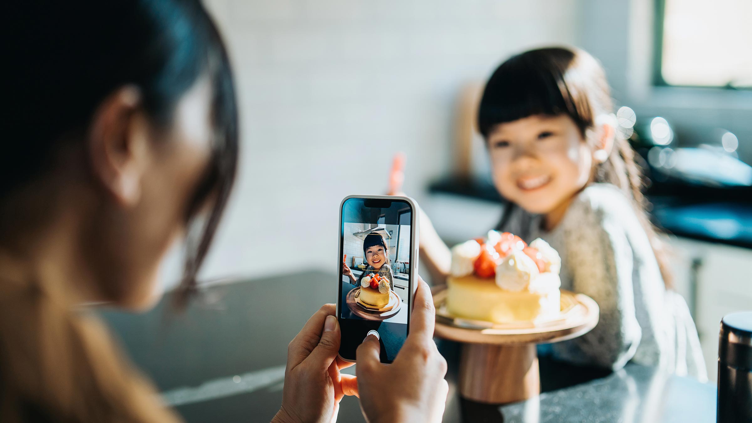 A mother takes a picture of her daughter with a cake