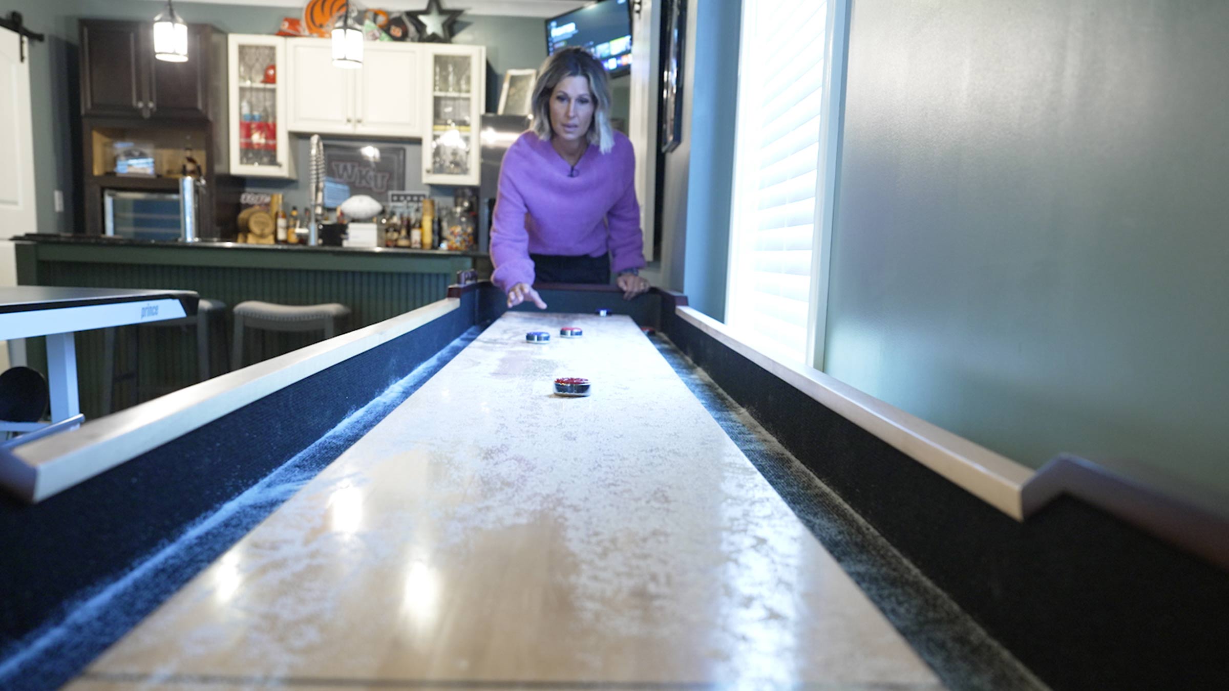 Chasity Harney playing shuffleboard in her kitchen