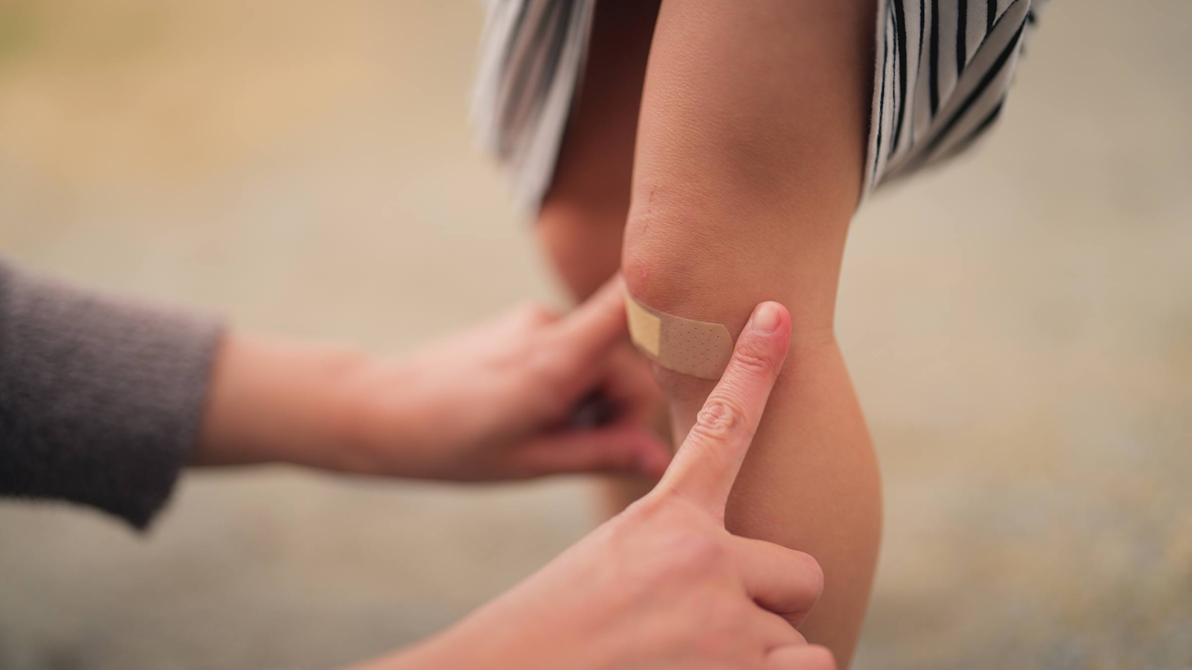 A mom puts a bandage on her child’s knee