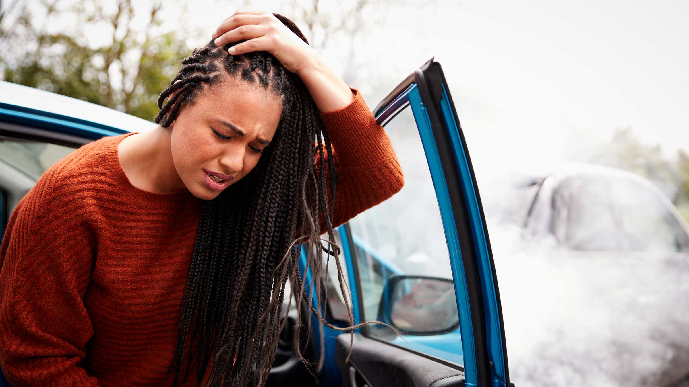 Female getting out of a car holding her head in her hands