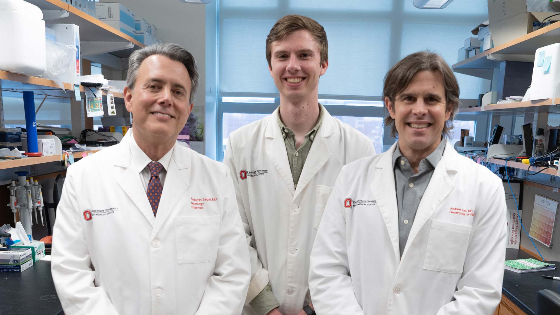 Dr. Benjamin Segal, MD, Dr. Andrew Jerome, PhD, and Dr. Andrew Sas, MD, PhD standing in a medical laboratory for a team picture.