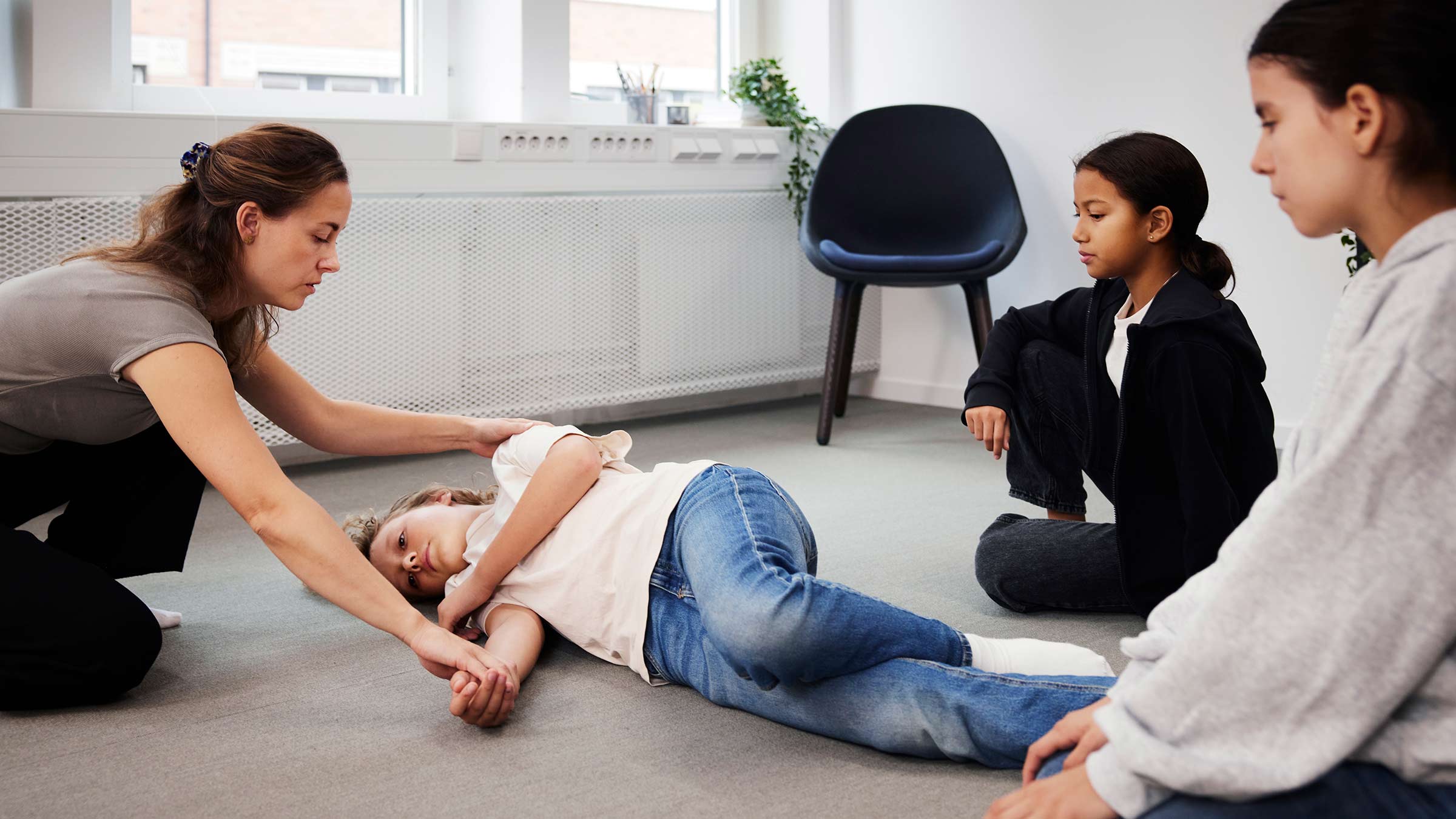 Teacher showing how to roll a person to a safe laying on a side position