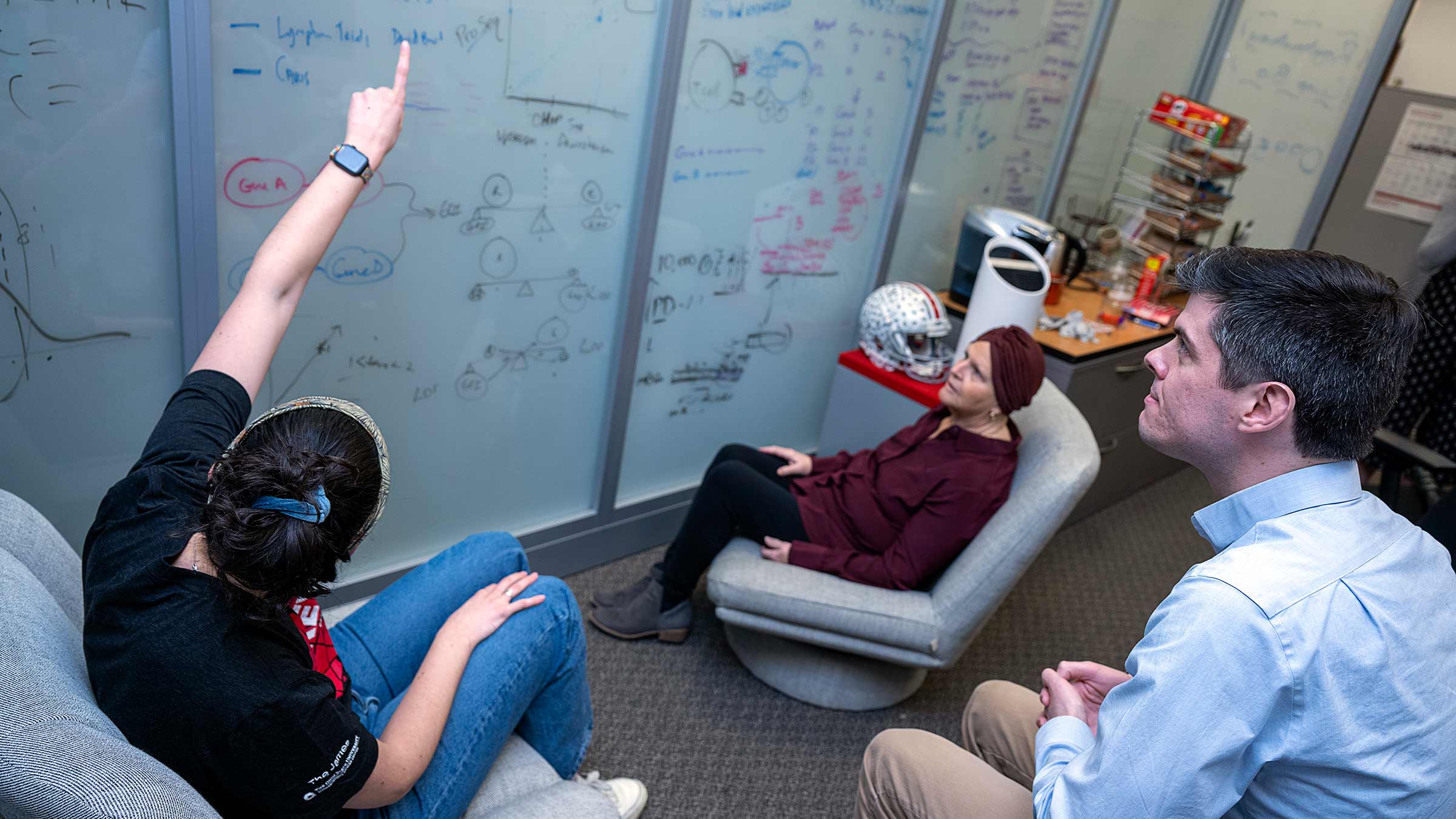 A patient in front of a whiteboard with the members of the Roychowdhurry Lab