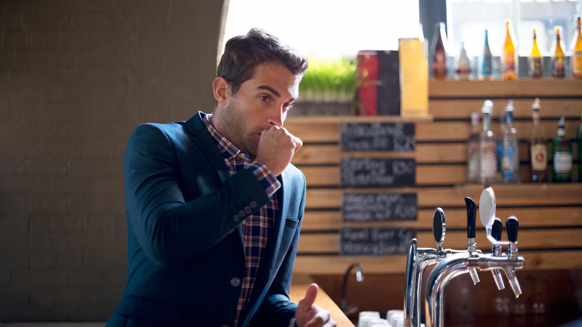 A young man covering his mouth mid hiccup with a closed fist