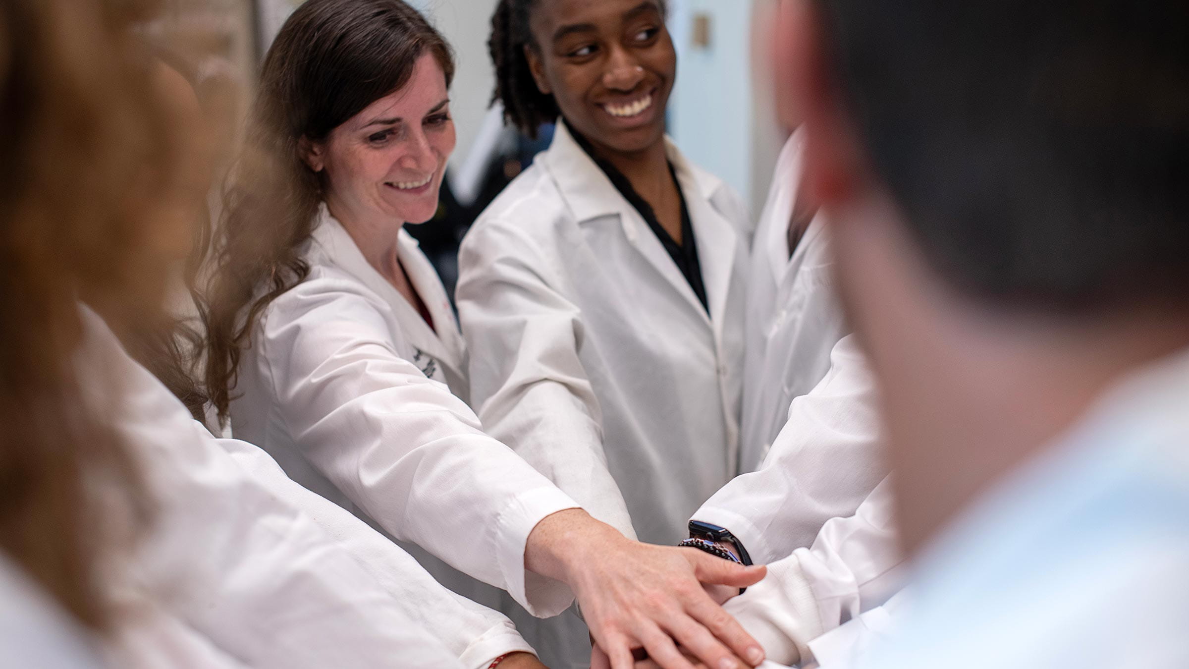 Dr. Sizemore and her team joining their hands in a huddle