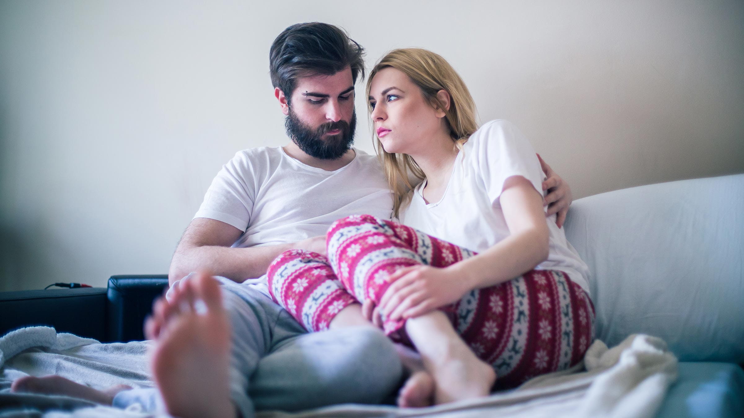 A young couple in pajamas sitting together in bed in the morning