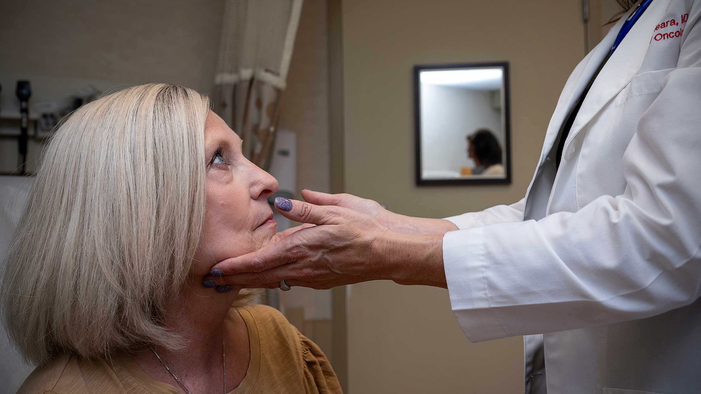 Dr. Meara lifts a patients chin to examine the mouth and throat