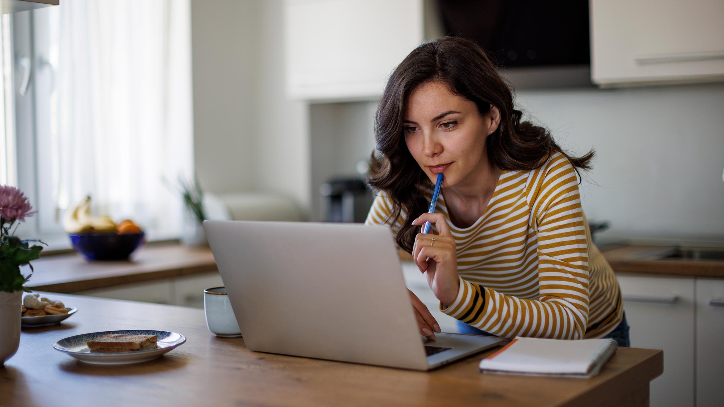 A young woman using a laptop in her kitchen