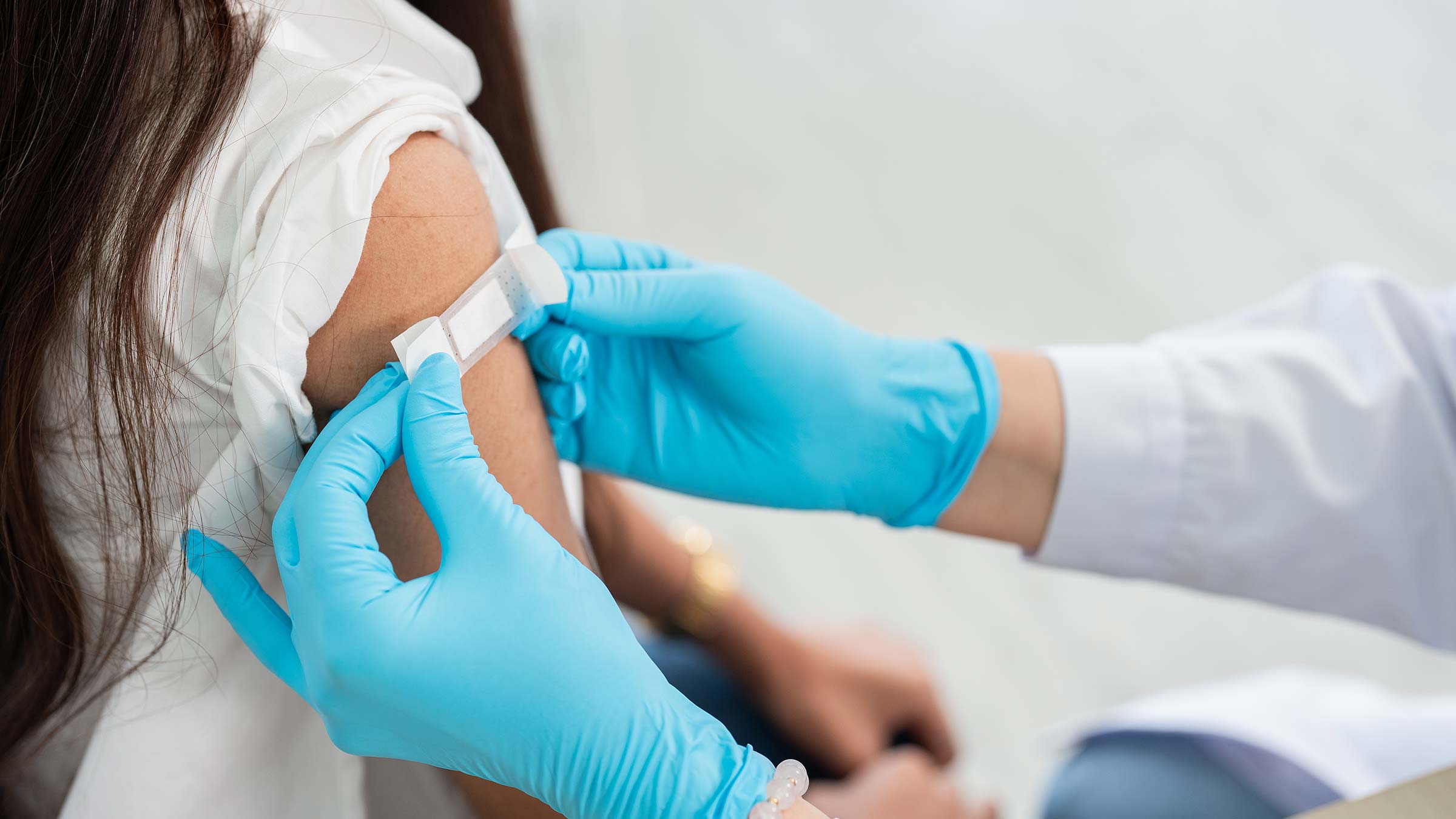    A bandage is applied on a young woman’s arm after administering a vaccine