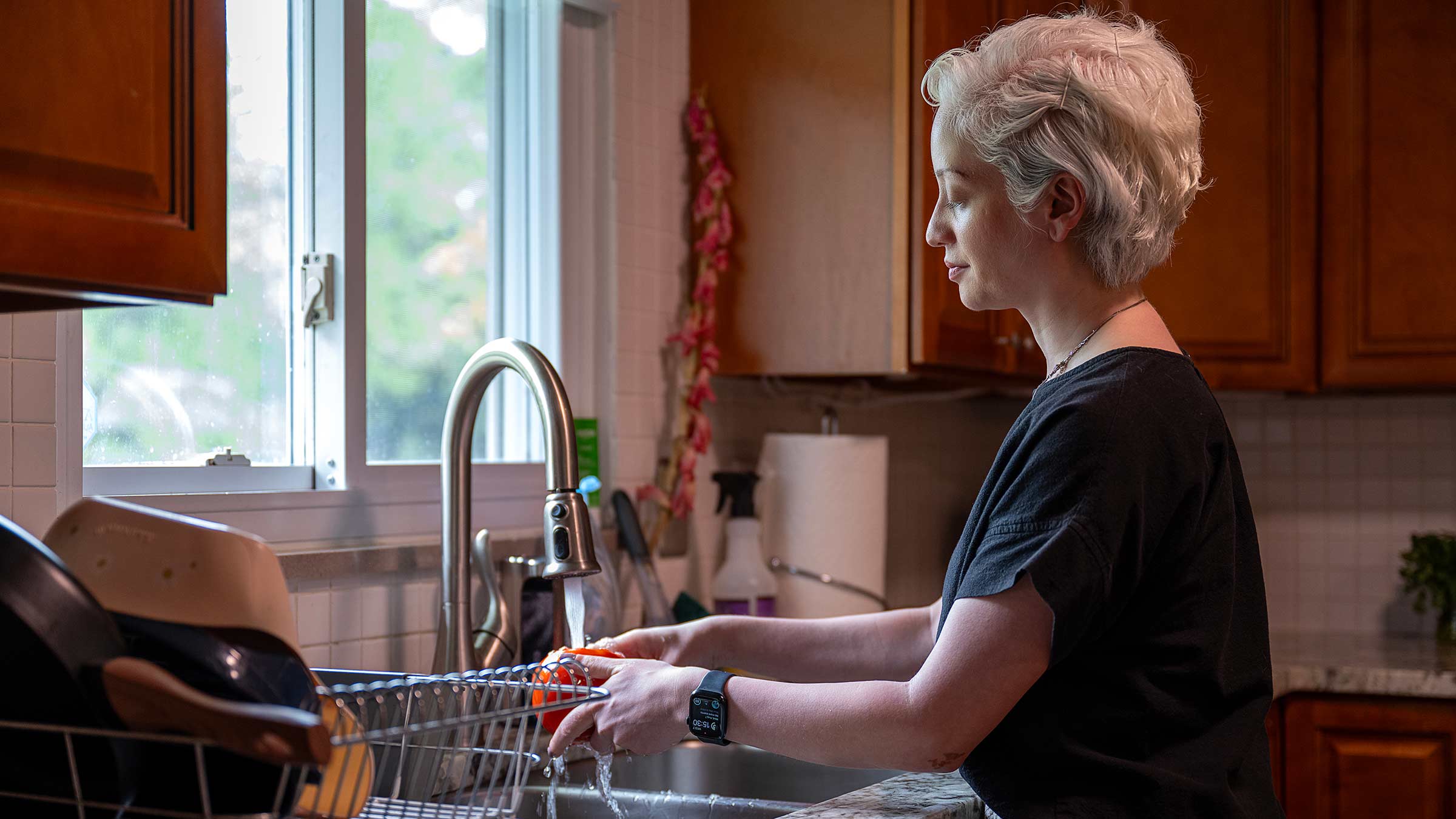 Sam de Silva washing produce at her kitchen sink in her home