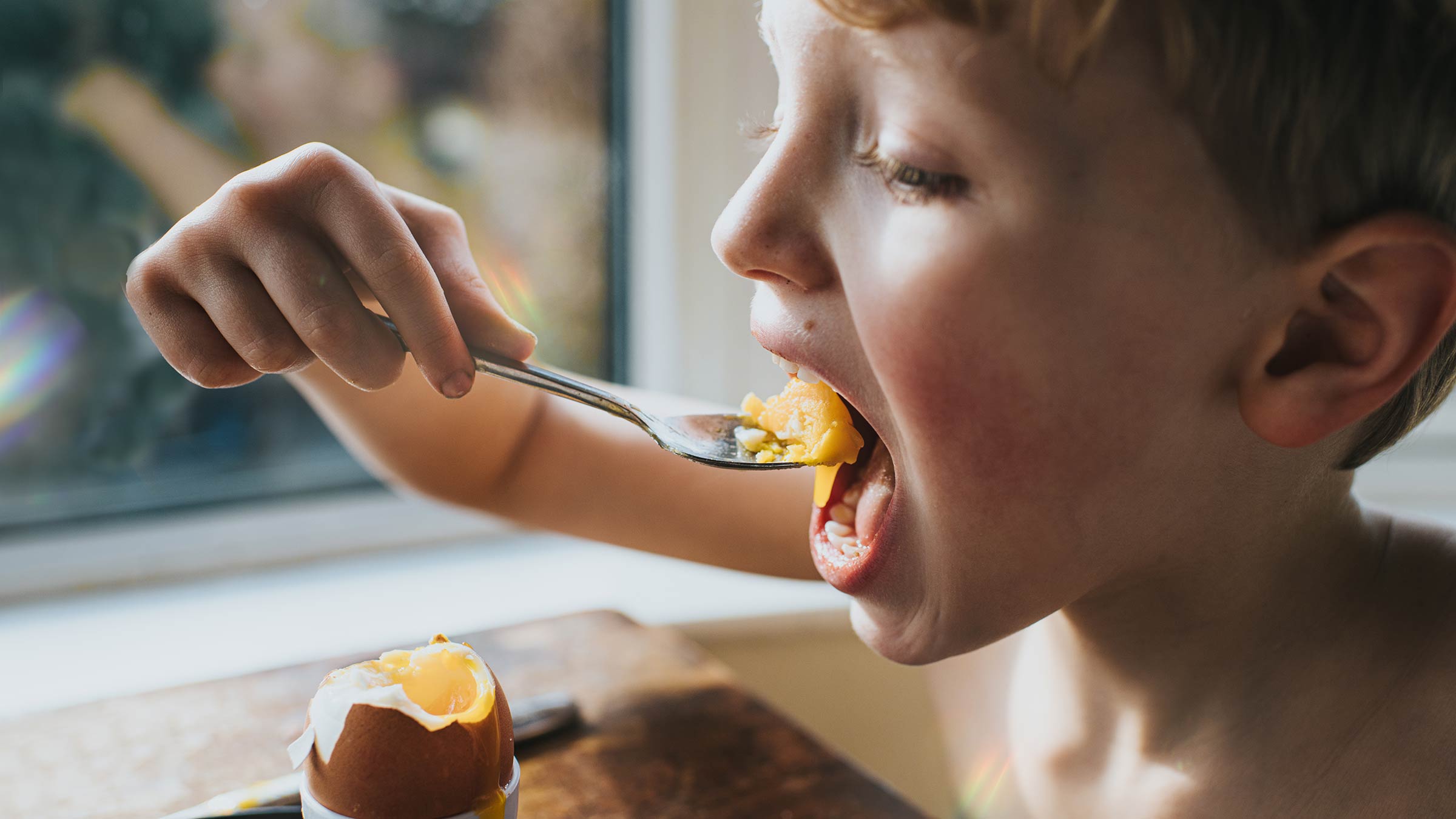 Young boy eating a soft-boiled egg