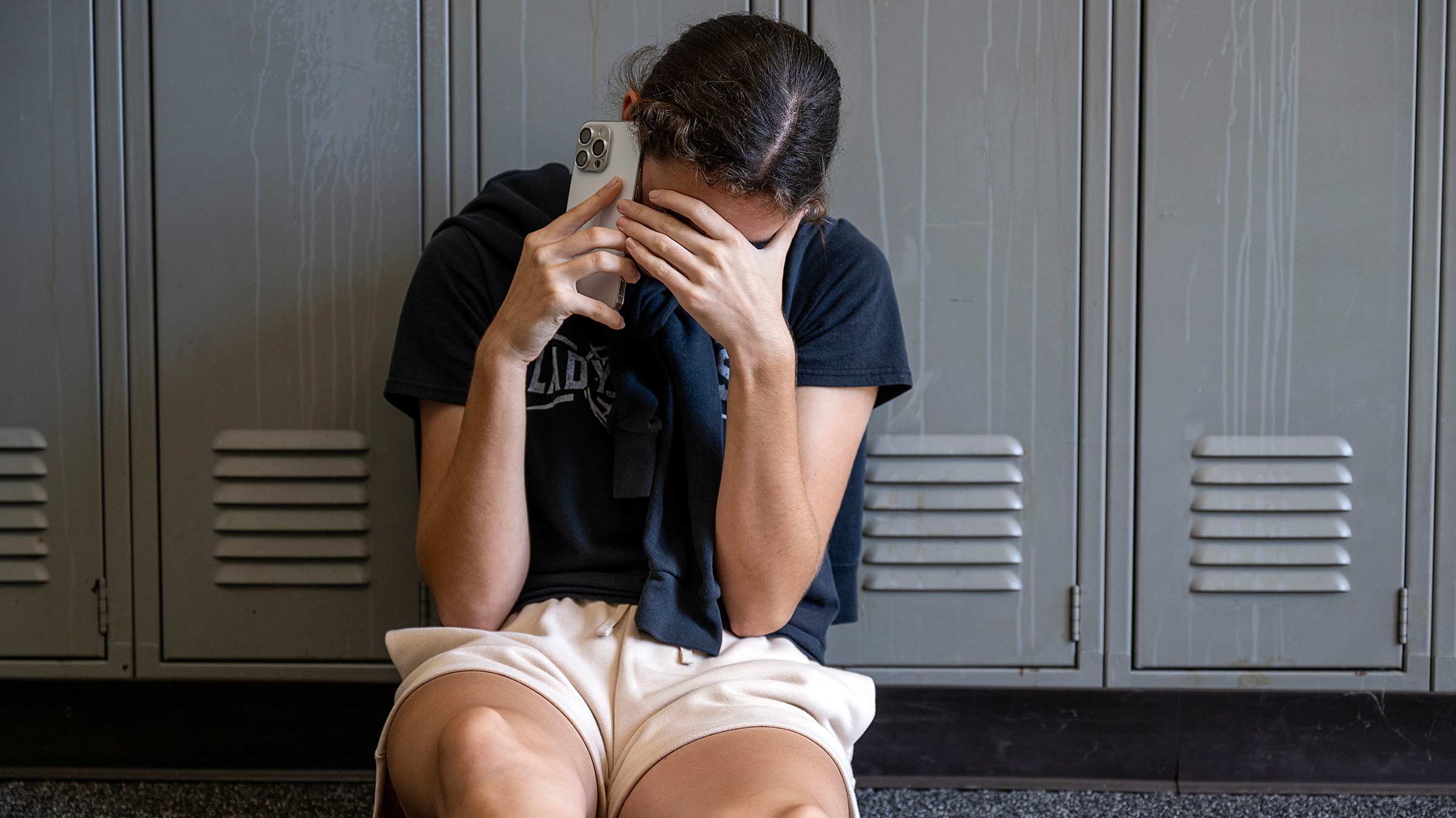 A teen talking on the phone covering their face