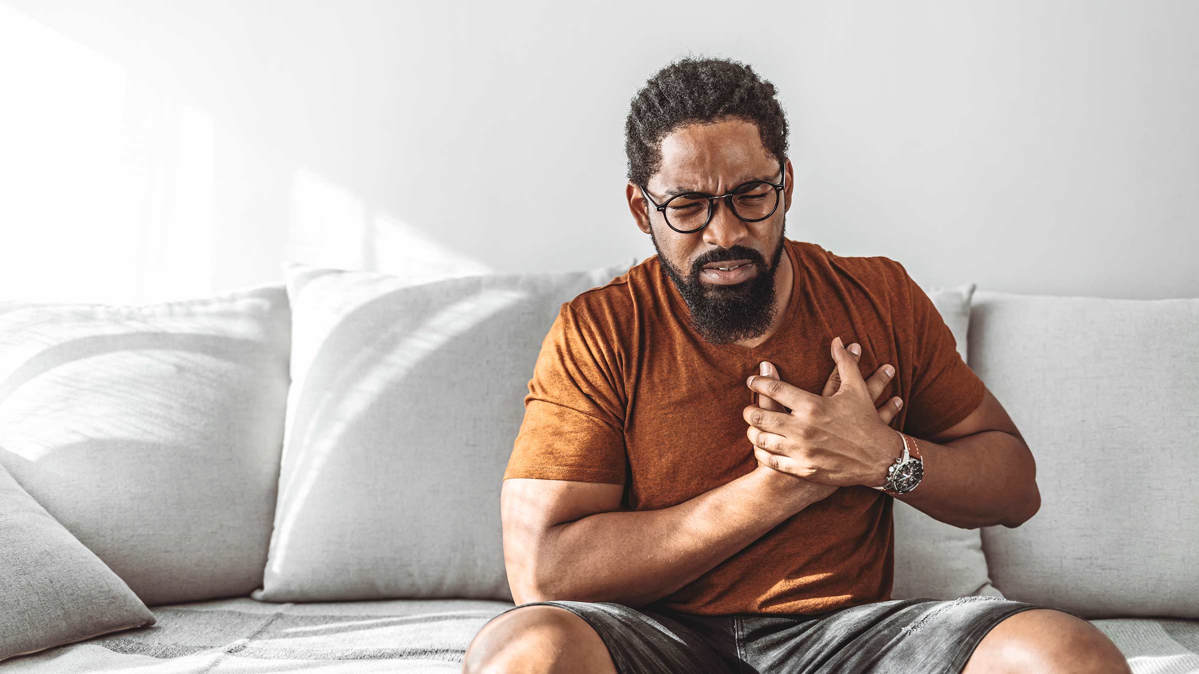 An African American man with chest pain holding his hands over his chest