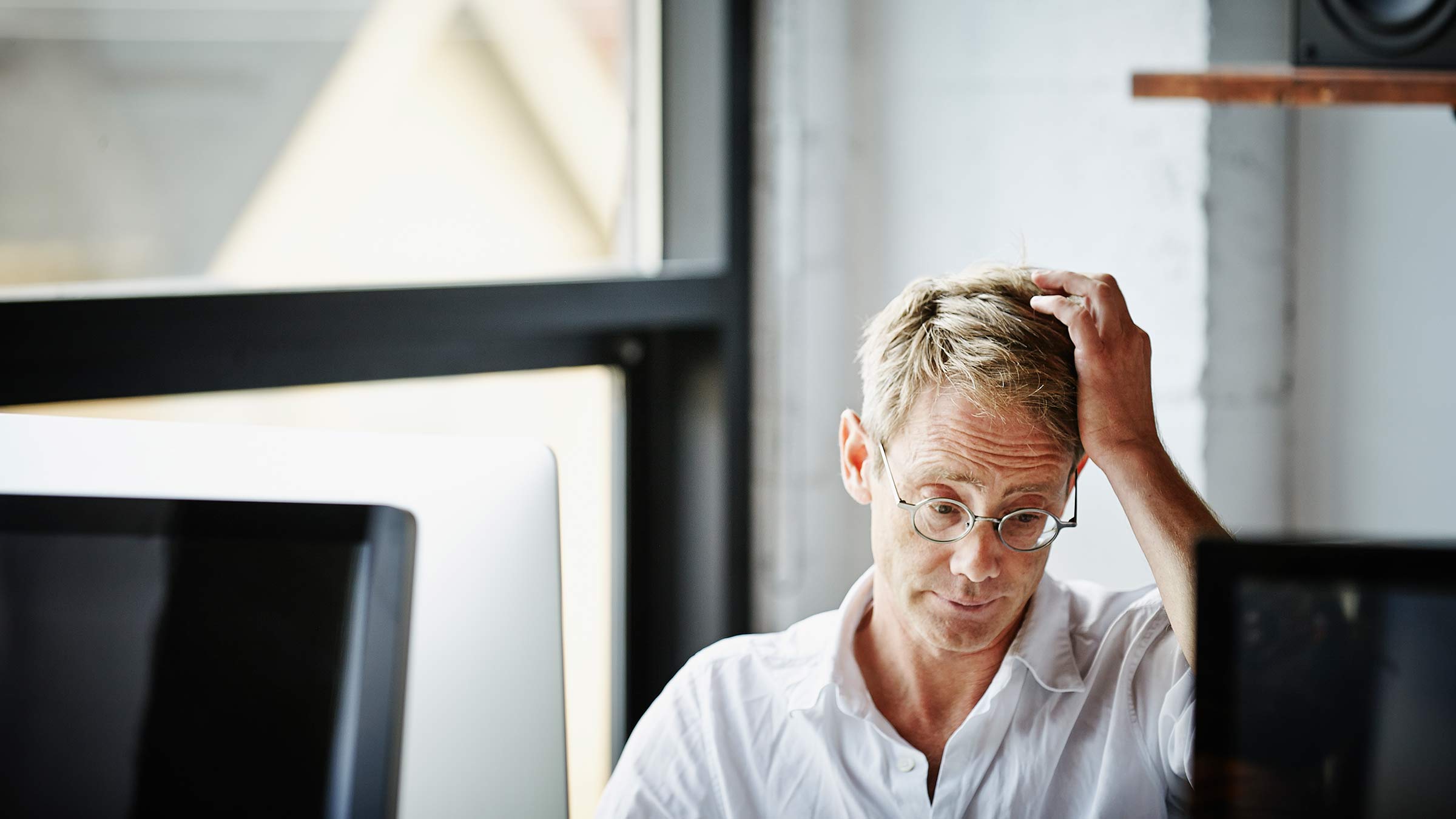 A man working at a computer with his hand on his head