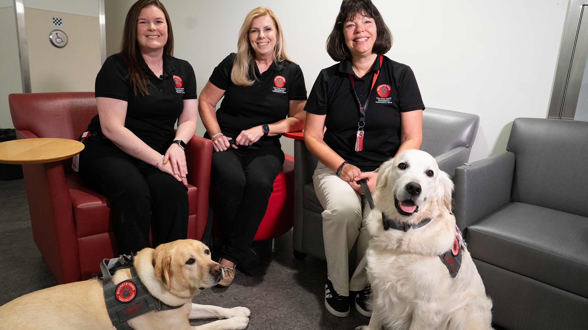 Three Buckeye Paws team members with two dogs in front of them