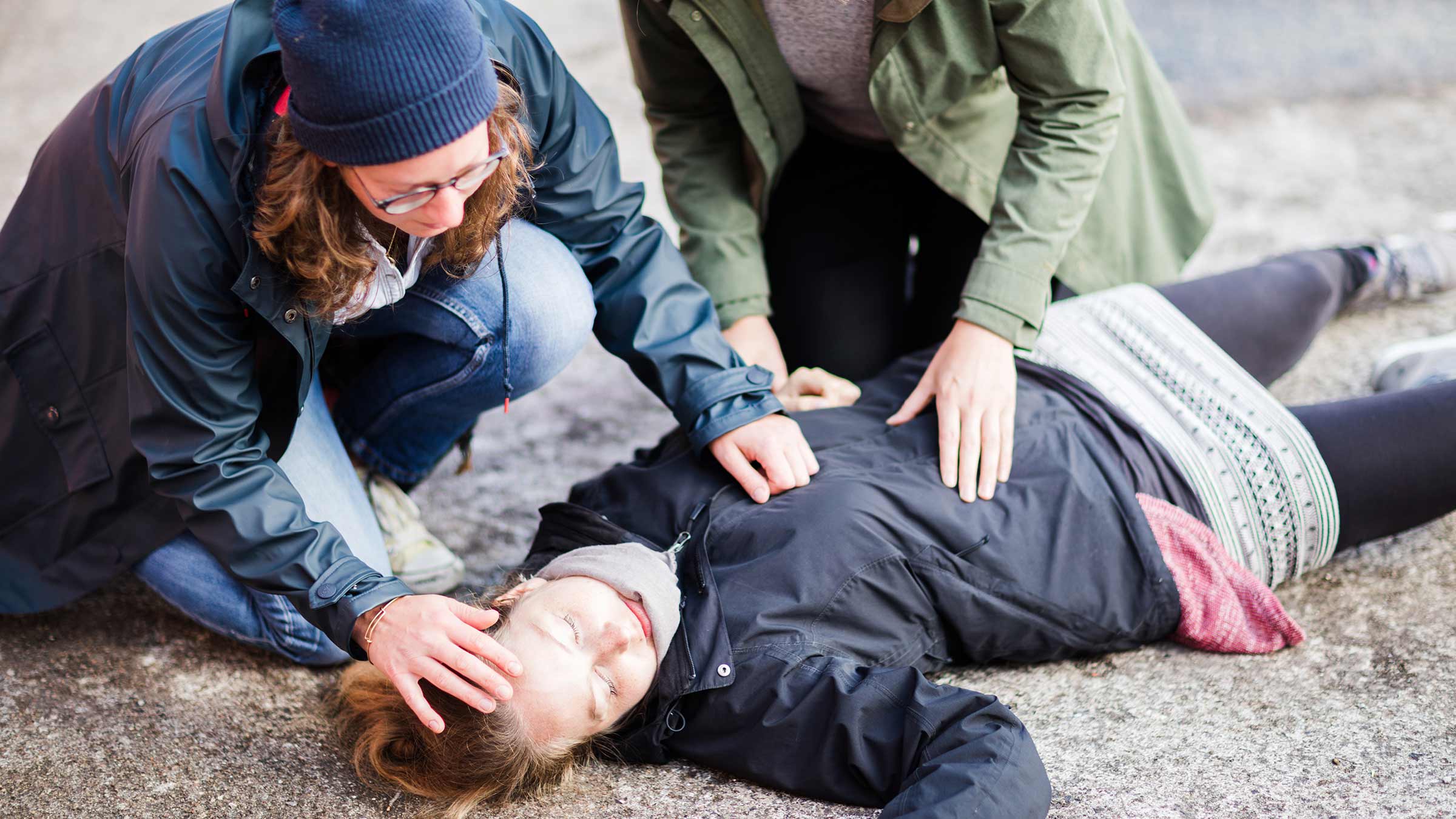 Two women looking after an unconscious woman