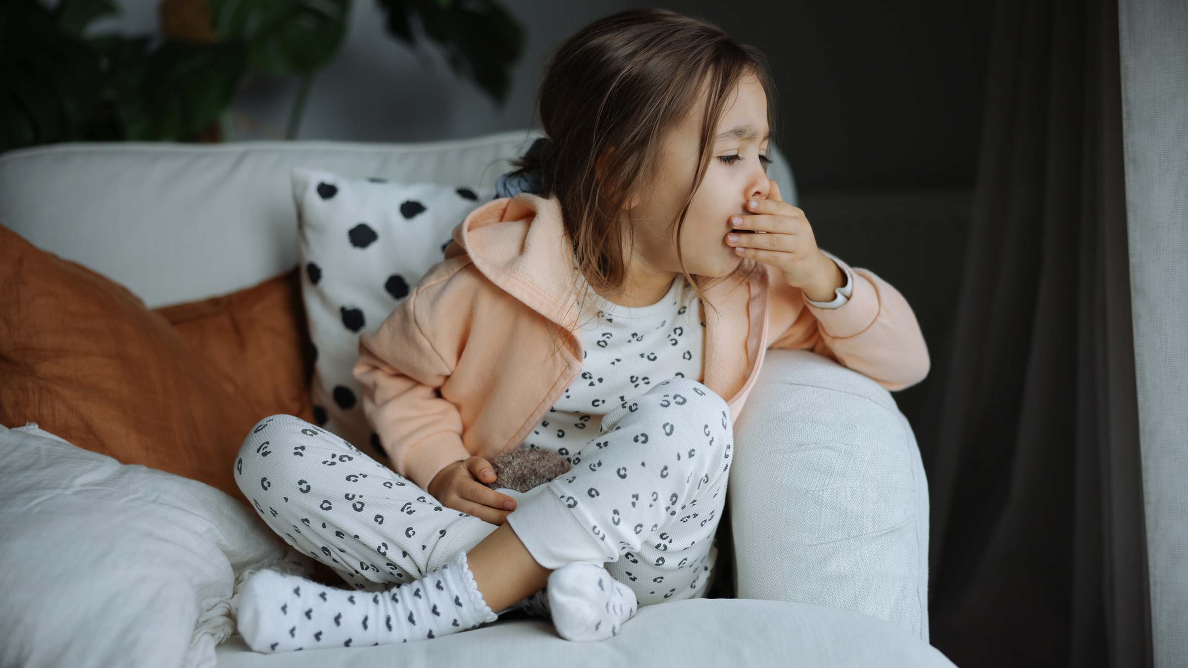 A little girl coughing on a living room couch