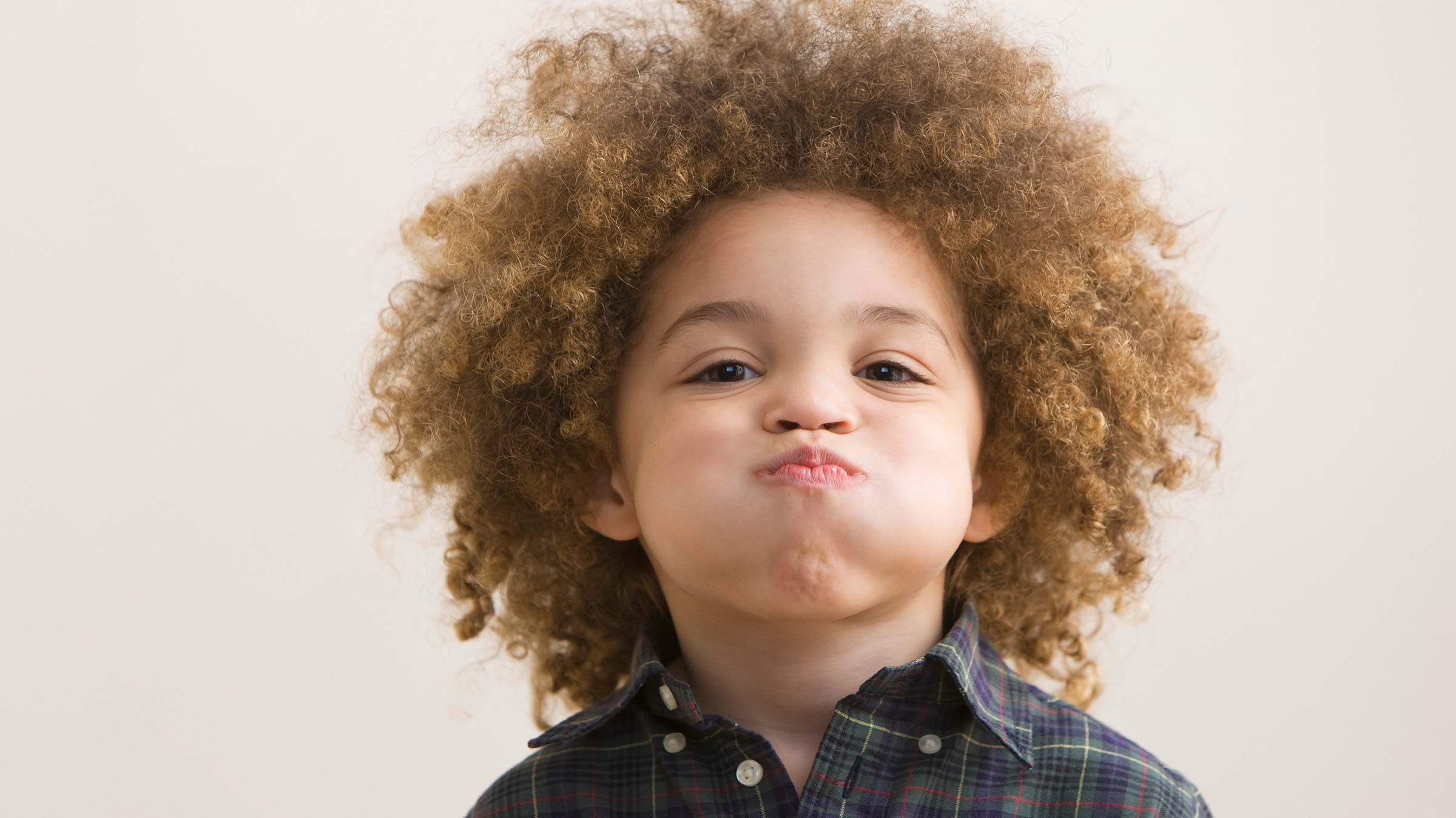 A little boy with puffed-out cheeks holding his breath