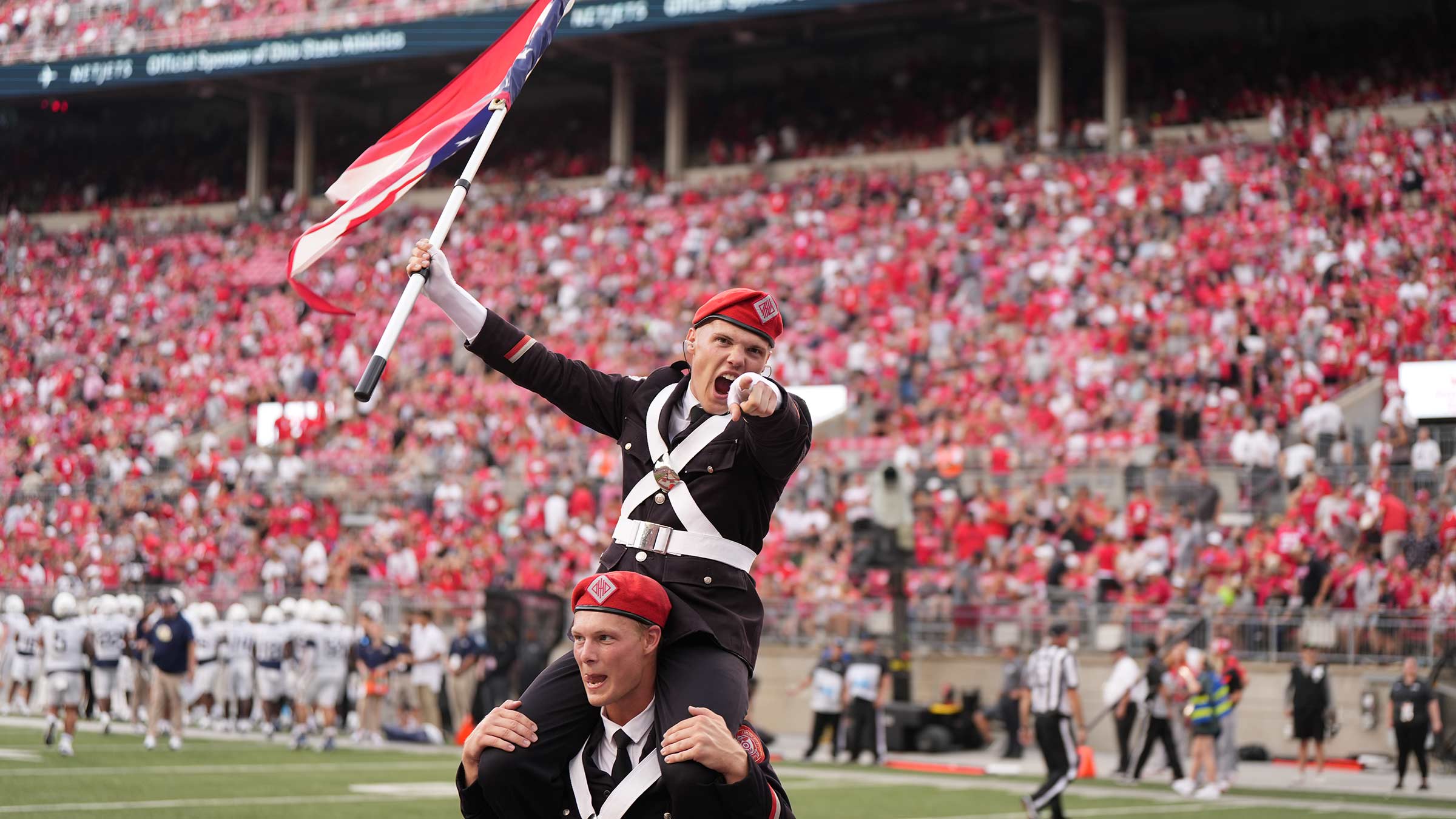 Grayson Niemi on the shoulders of a bandmate waving an Ohio flag