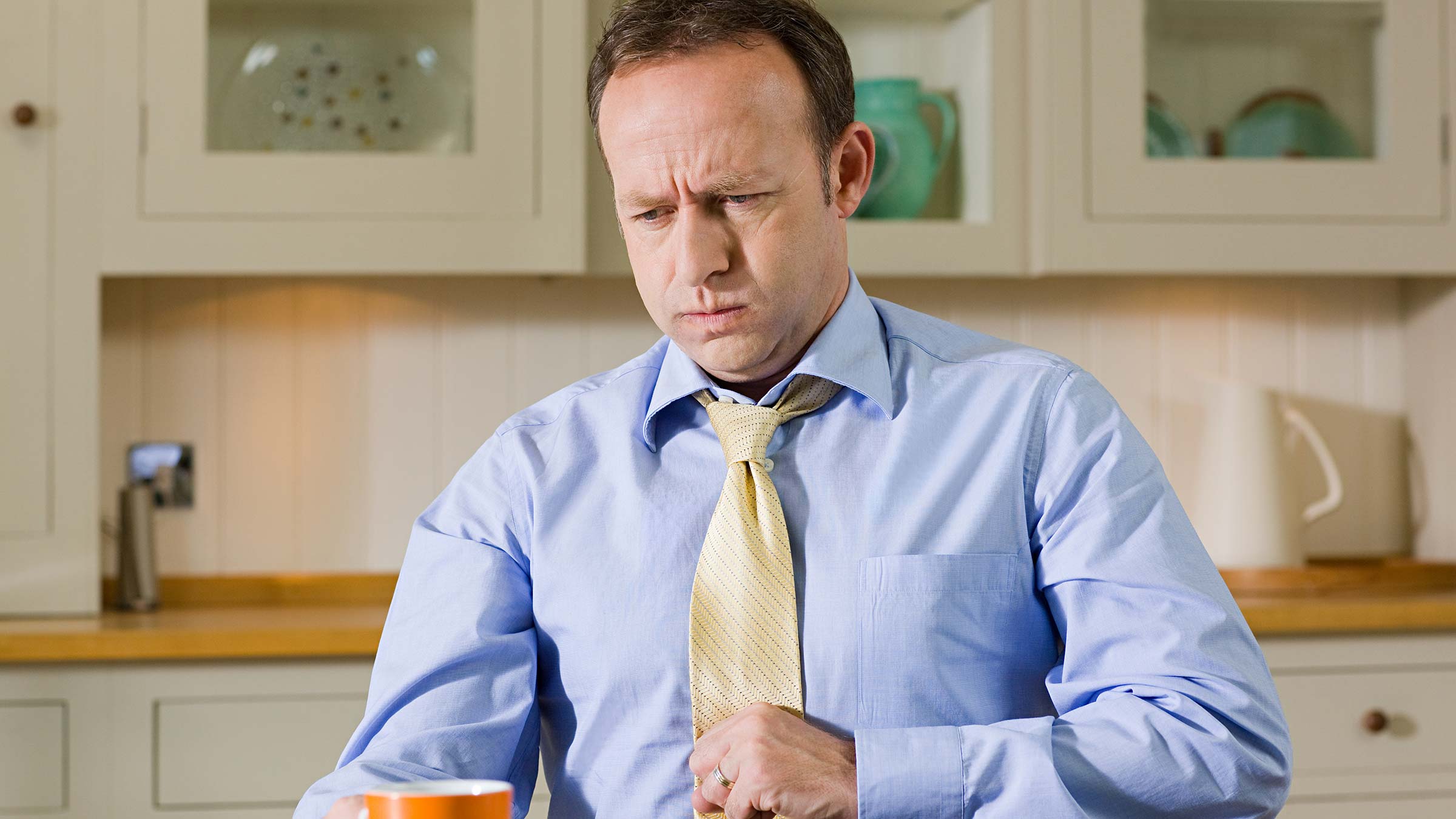 Man at his kitchen table struggles with indigestion