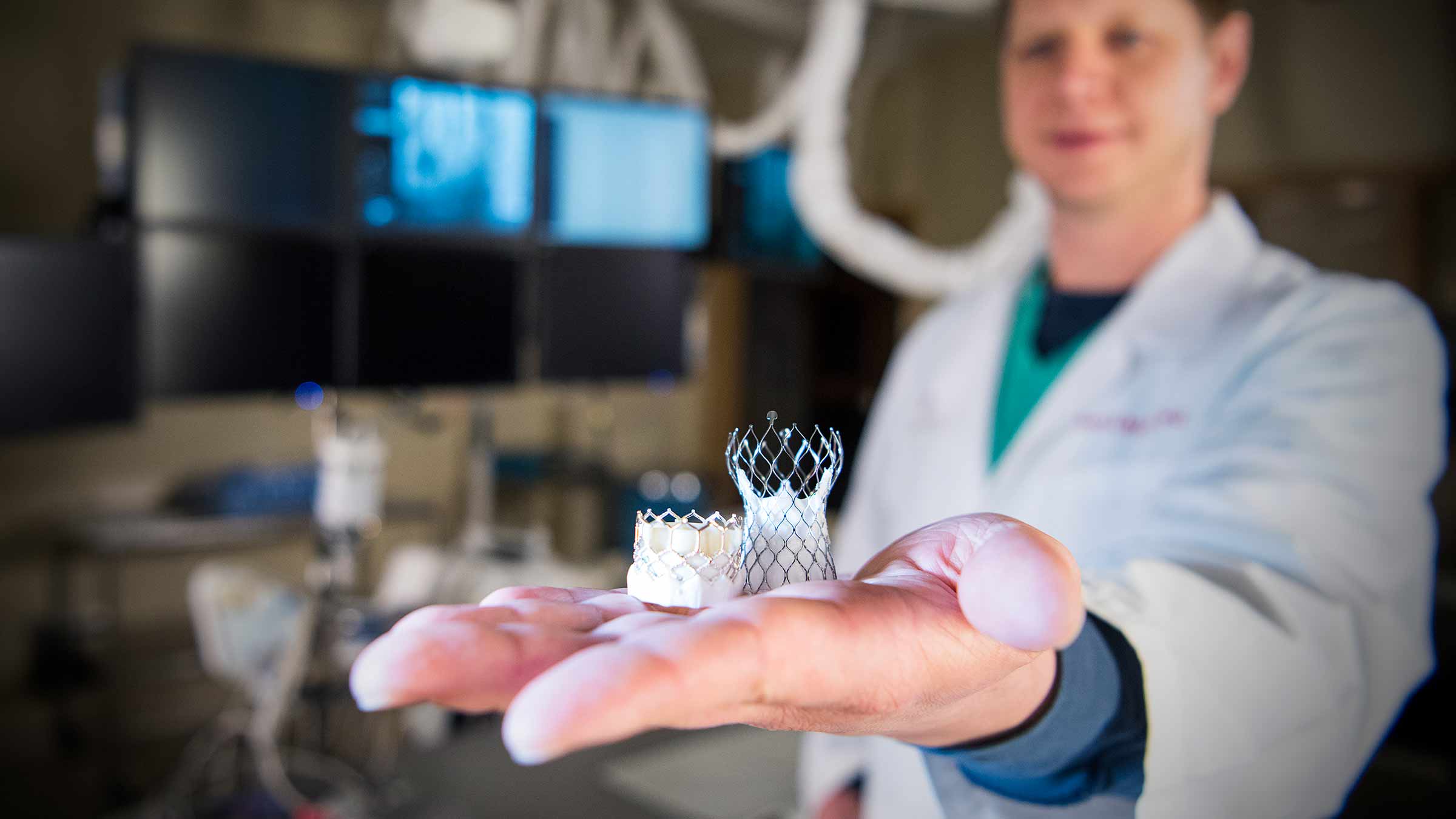 A doctor holding two aortic valve models on an outstretched hand