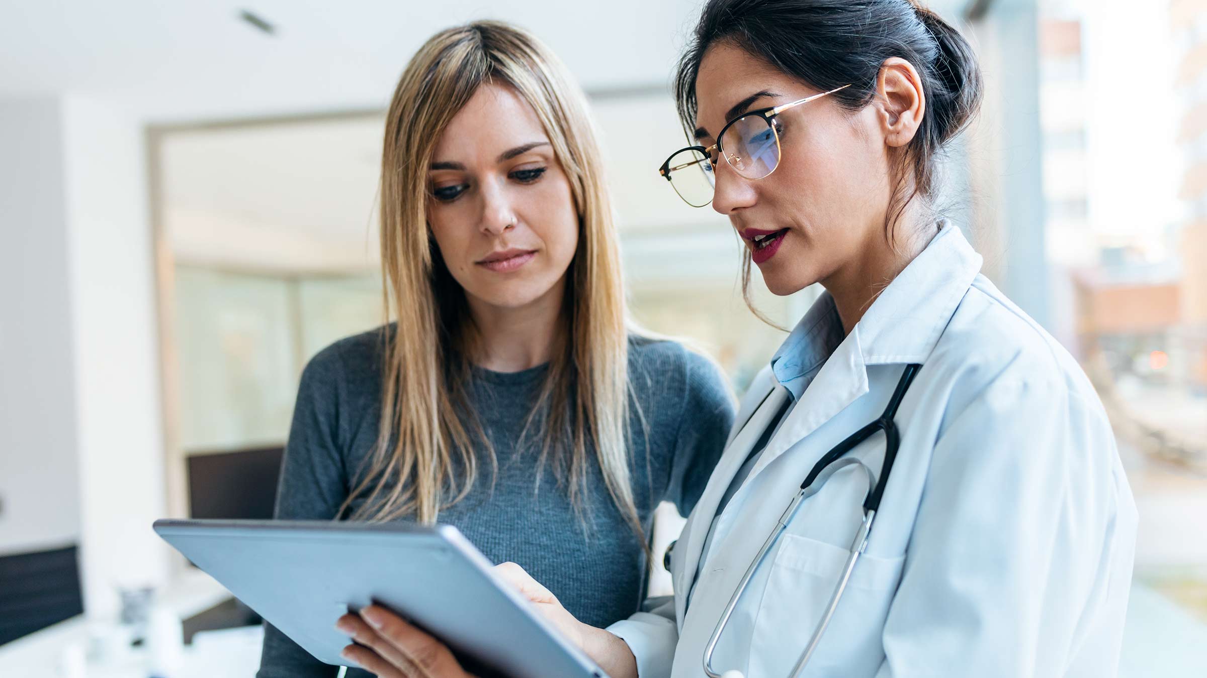 Female doctor consulting on a tablet to a patient in her 40s with pancreatic cancer