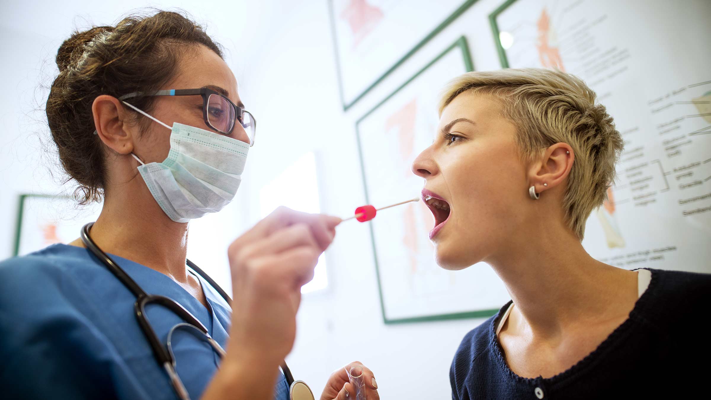 A nurse preparing to take a swab of a patient's mouth