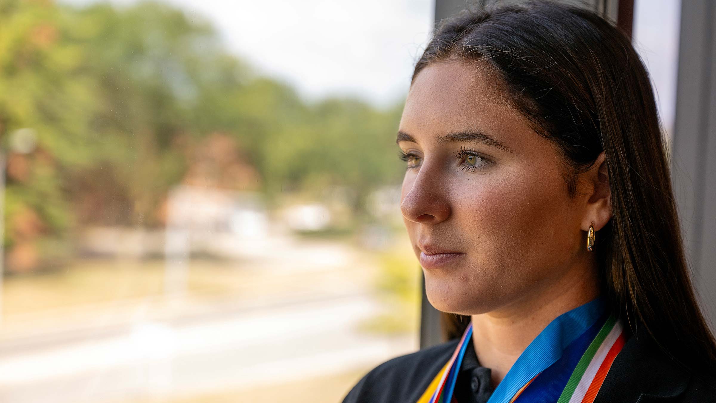 Melayna looking out the window wearing multiple medals