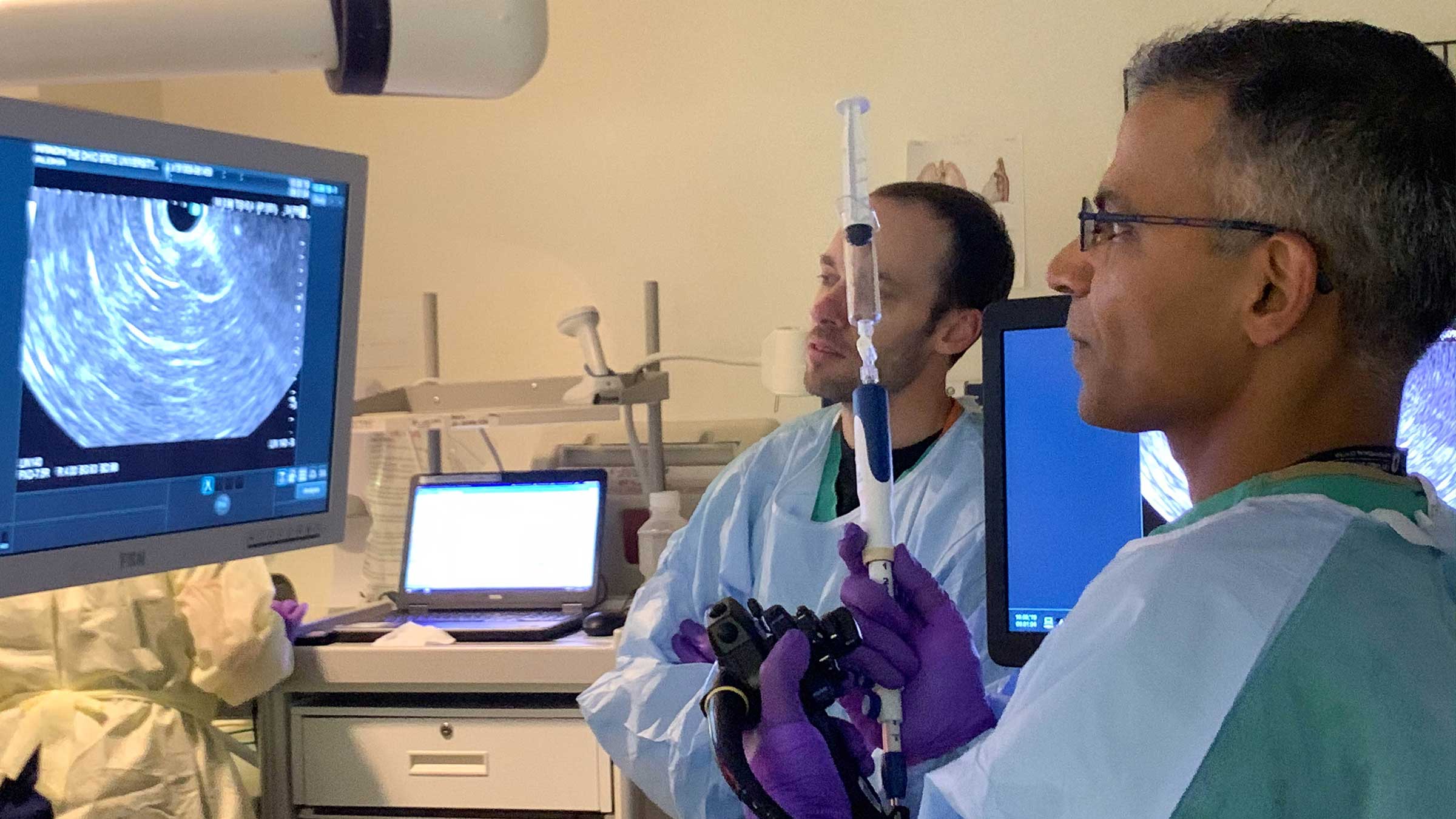 A doctor performing a "virtual biopsy" of the pancreas, viewing the cyst wall on screens