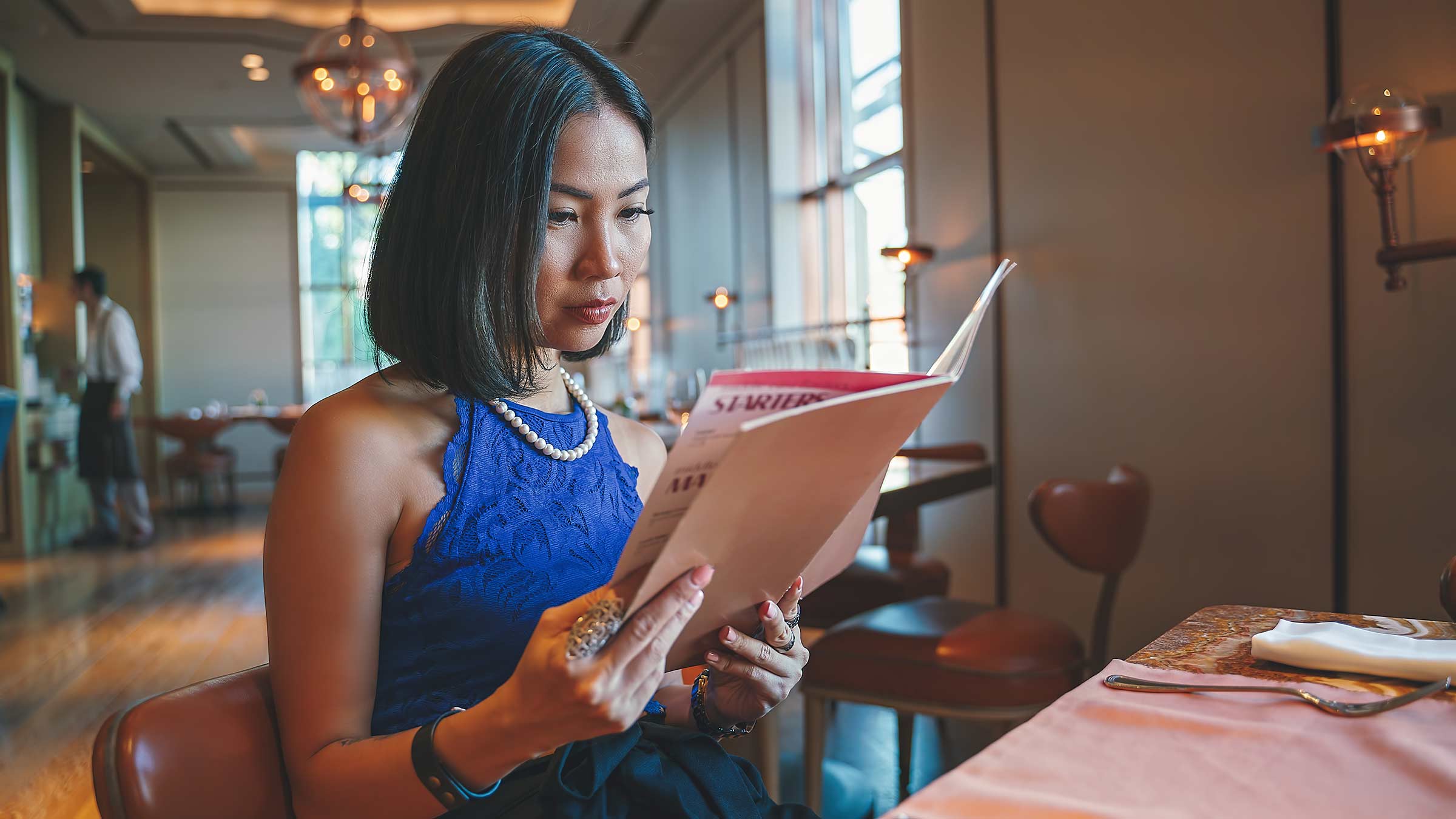 A woman reading a menu at a nice restaurant