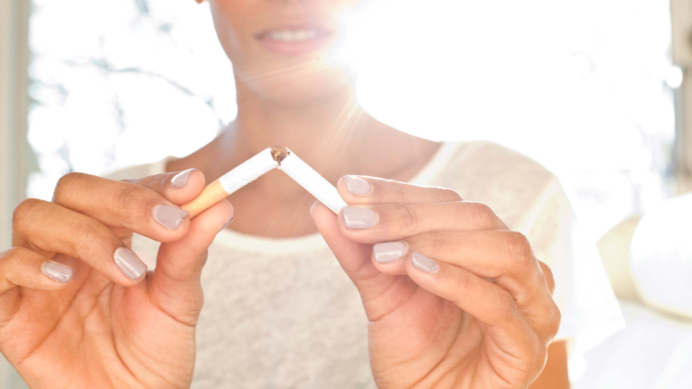 A woman breaking a cigarette in half