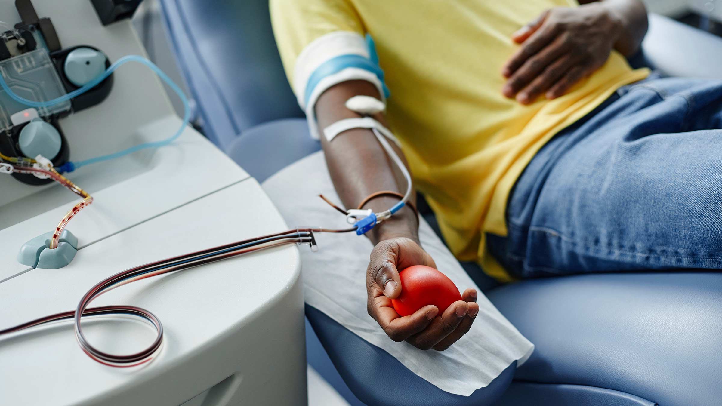 Man holding a soft ball in his arm while donating blood