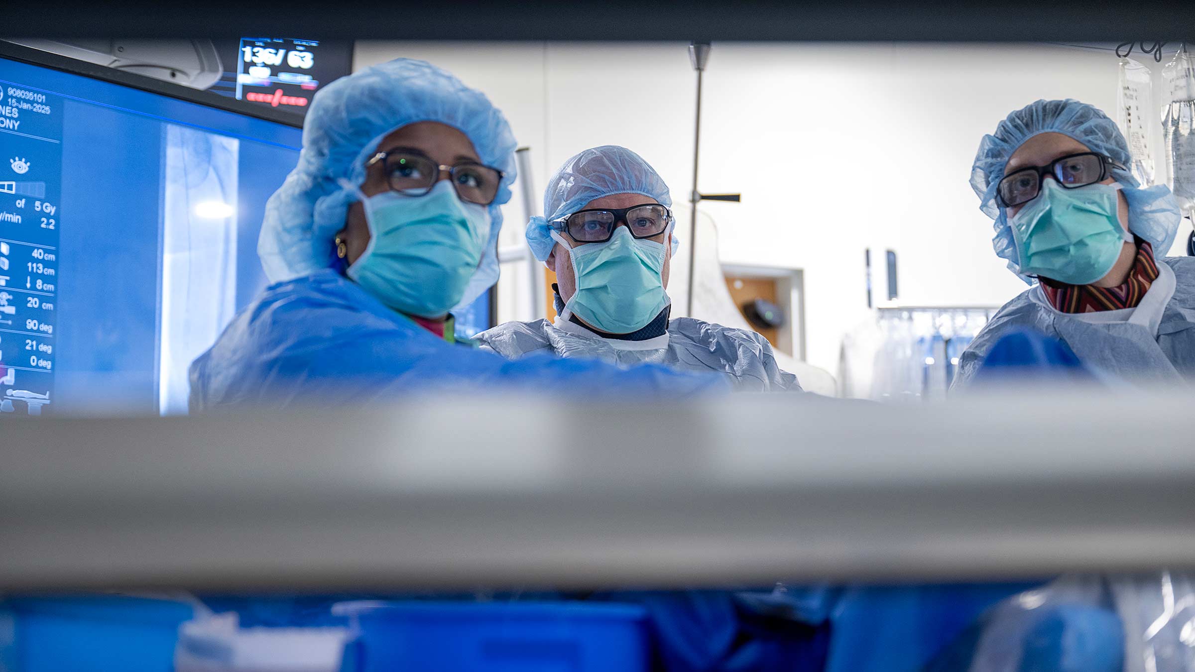 Three doctors looking up during a surgery