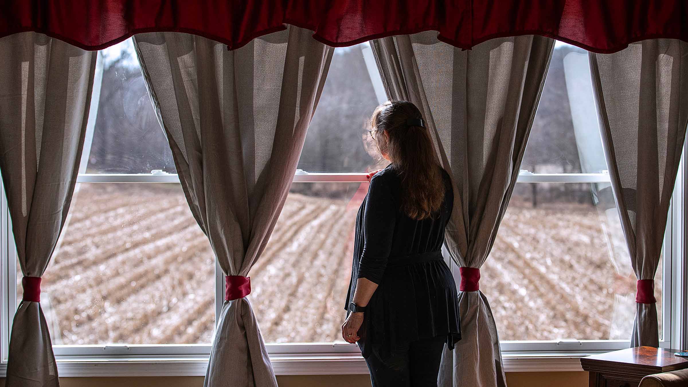 Judith Dann looking out the window in her home