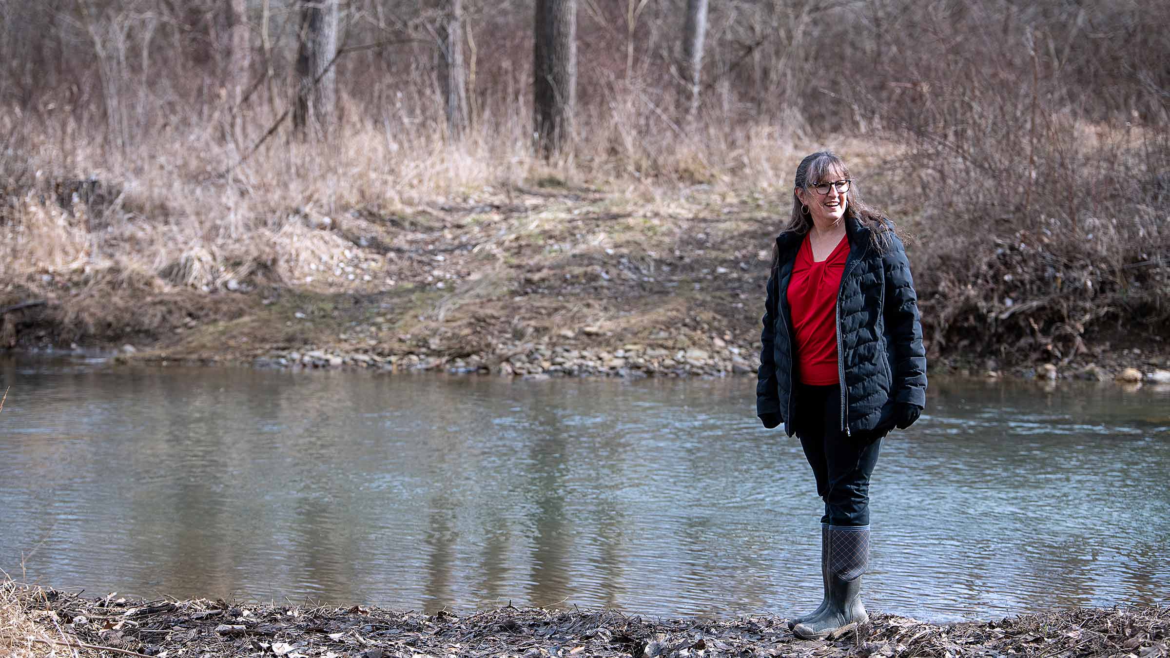 Judith Dann standing next to a river in the woods