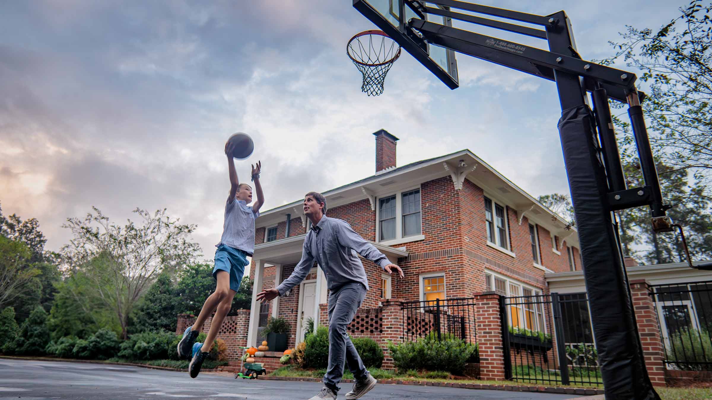 Byron shooting a ball into a basketball net while playing with his dad