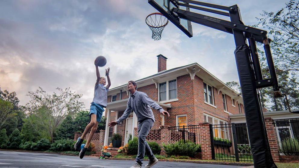 Byron shooting a ball into a basketball net while playing with his dad