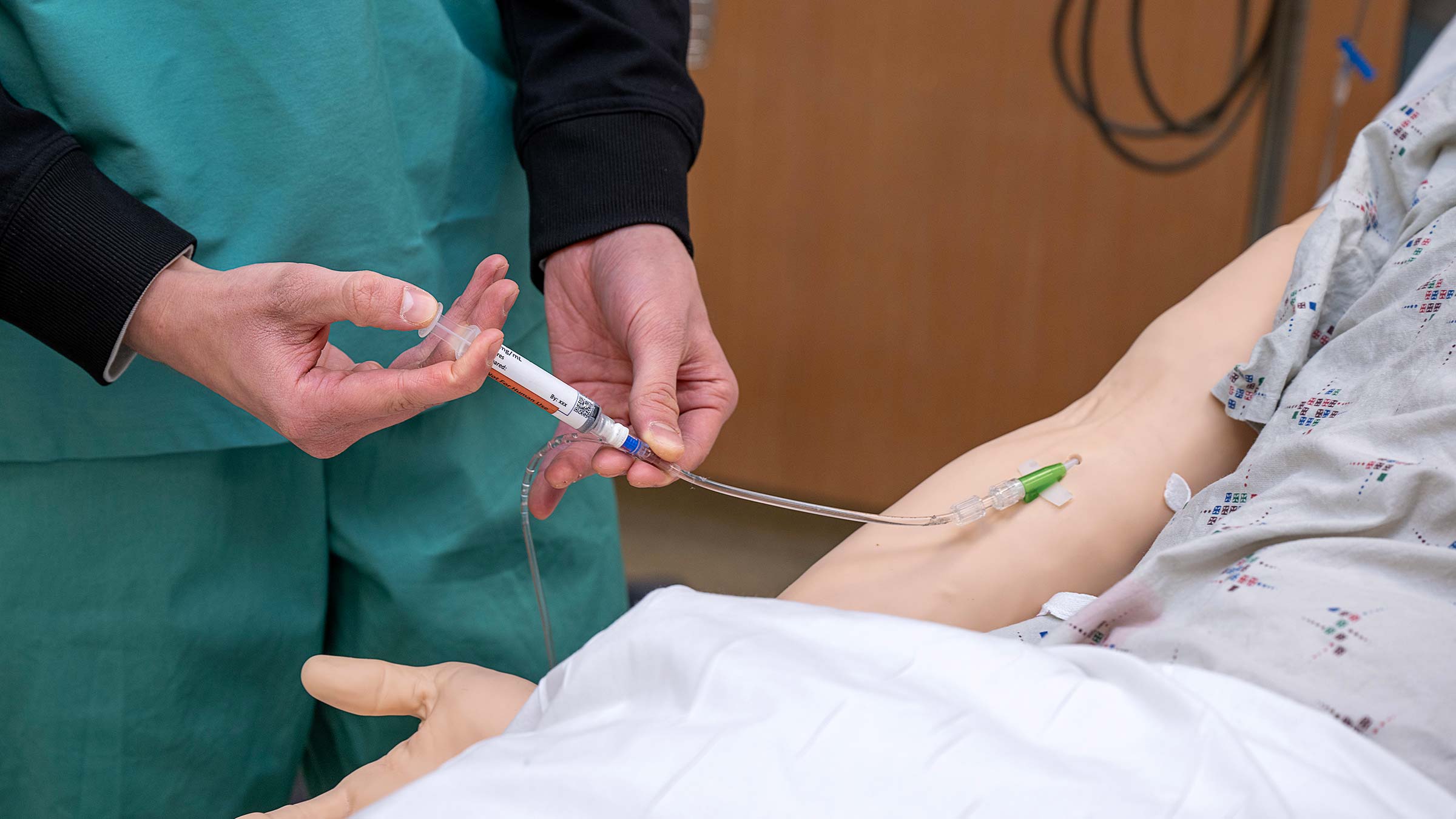 Student practicing administering IV fluid to a manikin