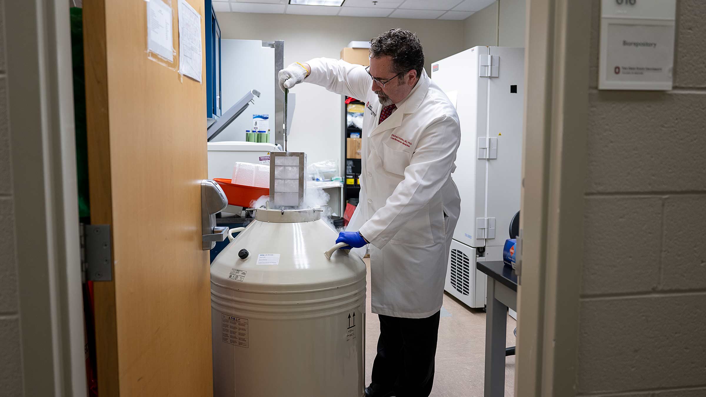 Richard Gumina lifting racks of test tubes stored in liquid nitrogen