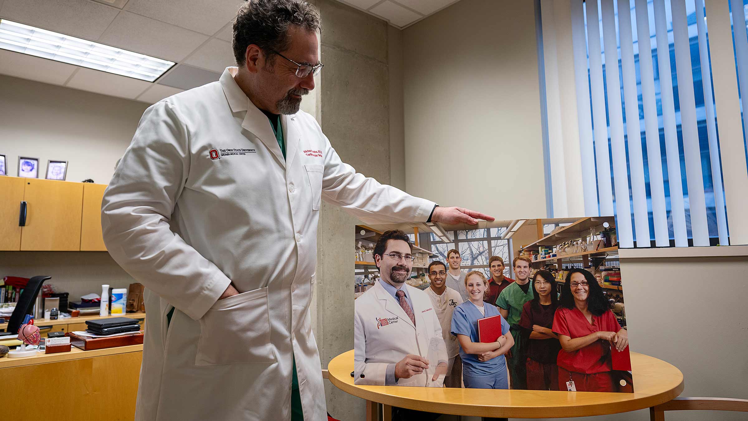 Dr. Gumina holding up a large photo of him with his colleagues