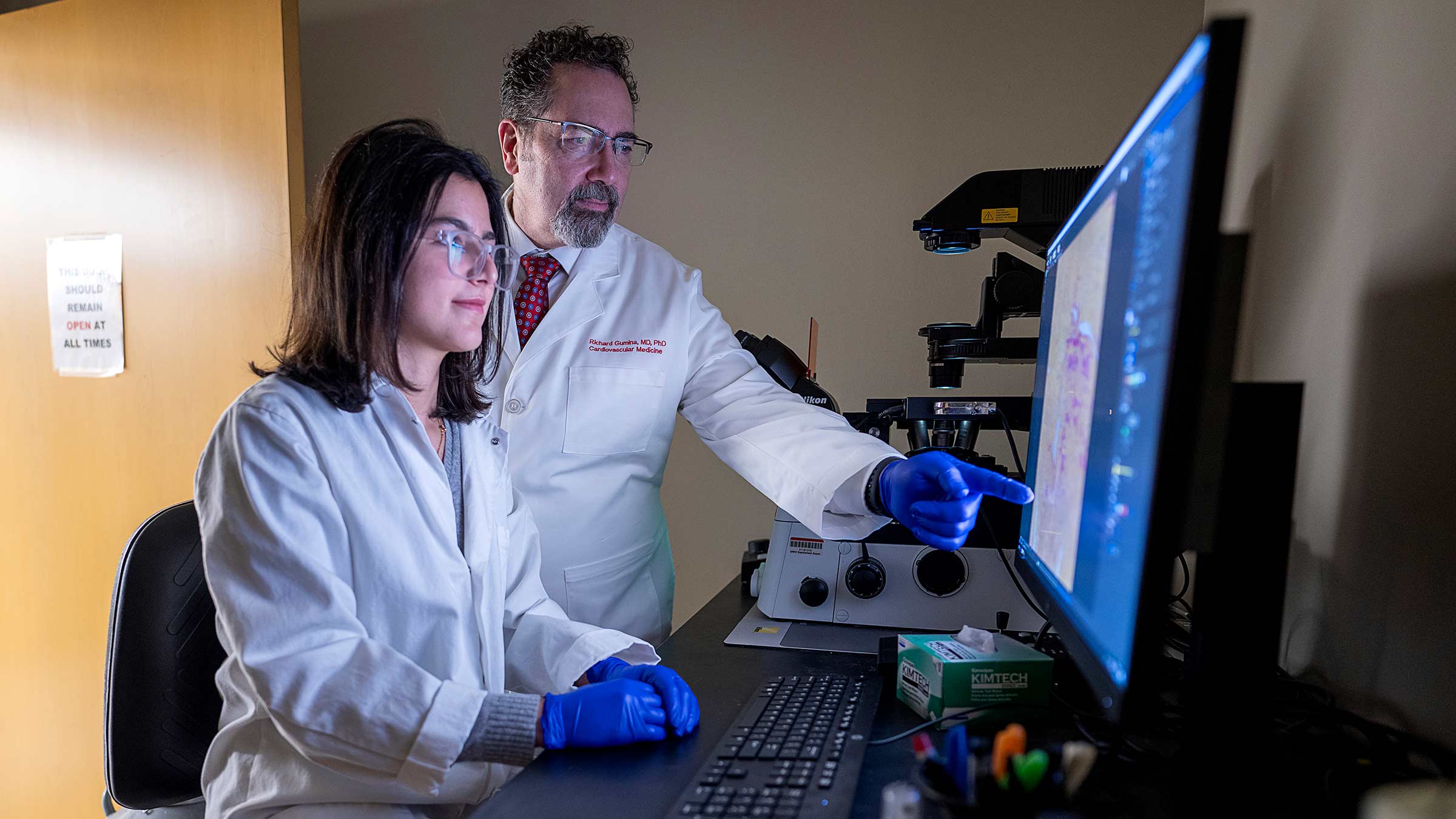 Dr. Gumina standing next to a student and pointing to a computer screen