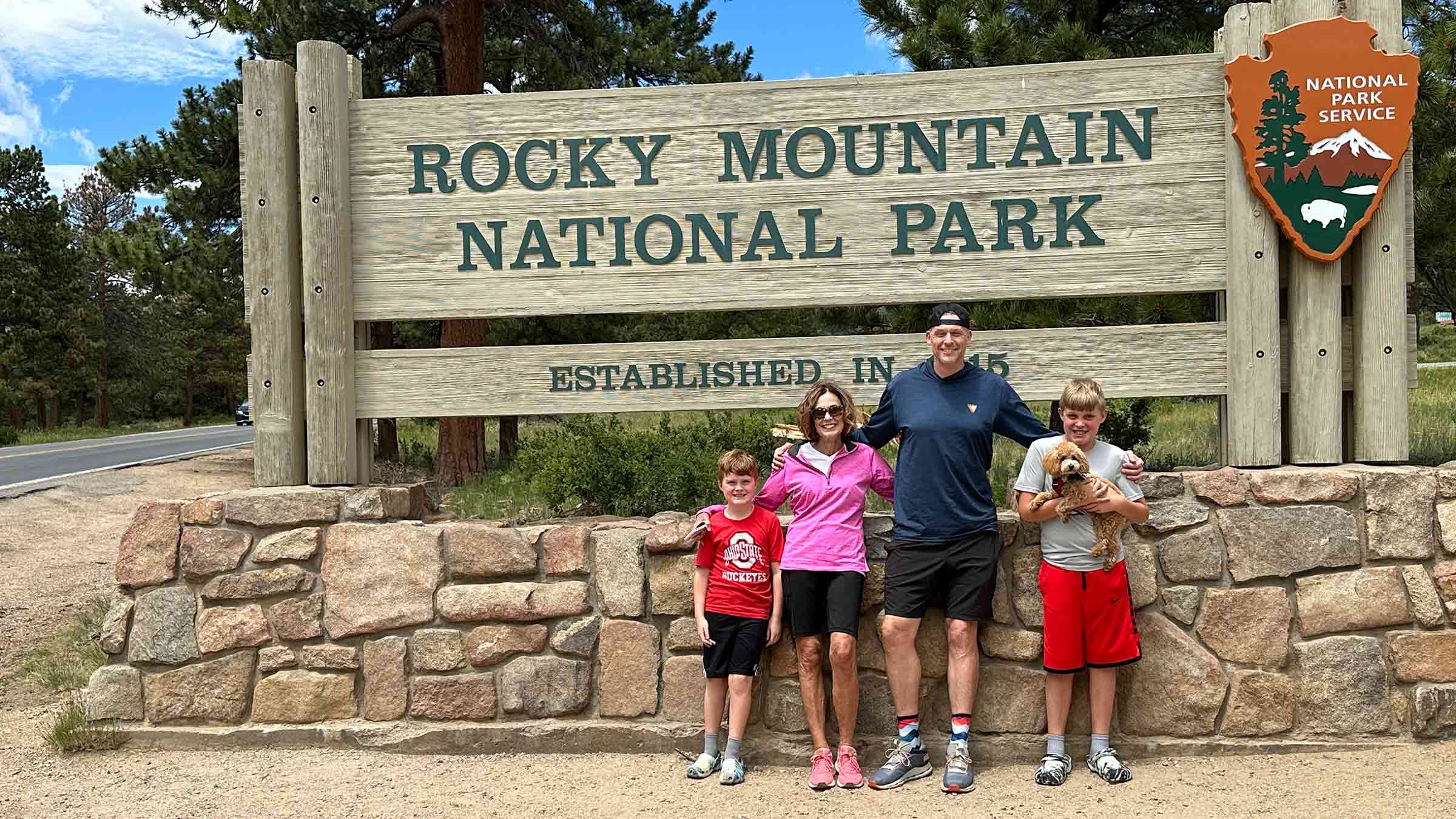 A family next to the "Rocky Mountain National Park" sign