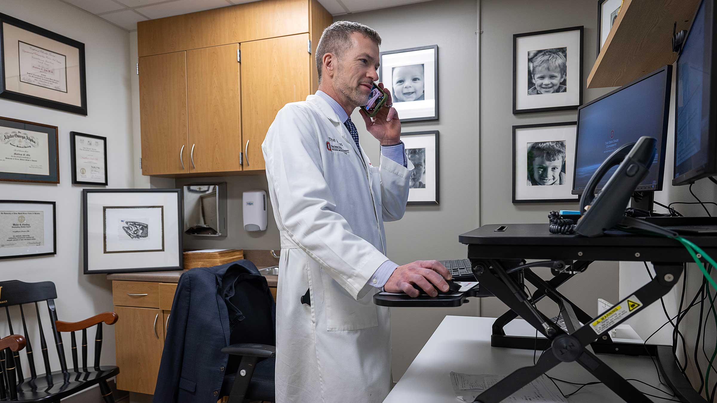 Dr. Old talking on the phone while working on the computer at his office