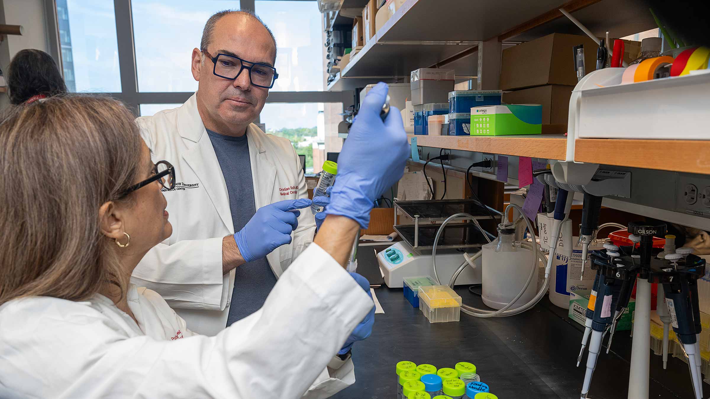Dr. Christian Rolfo viewing a collection of test tubes with a colleague