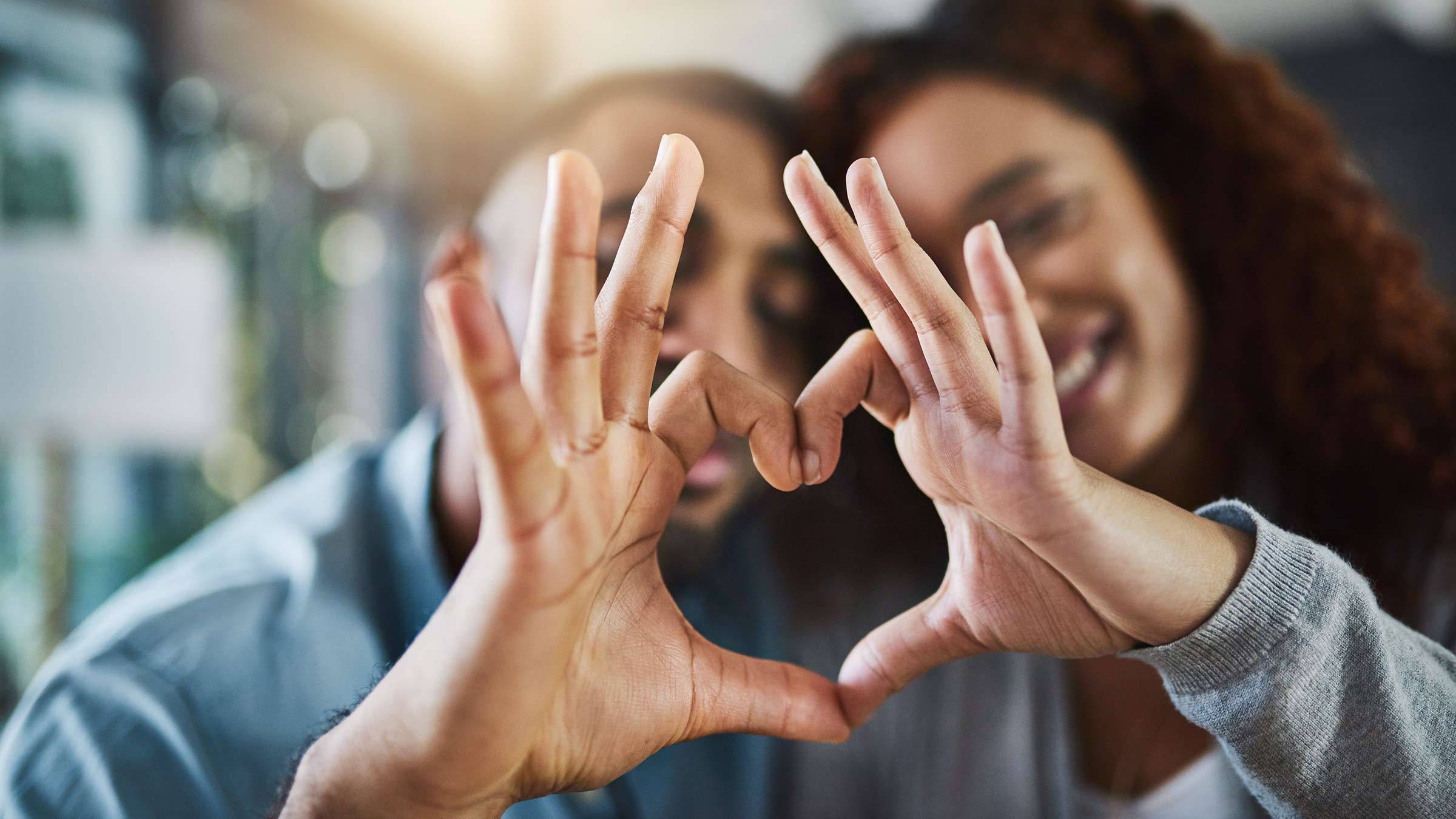 Two women holding their hands together to make a heart symbol
