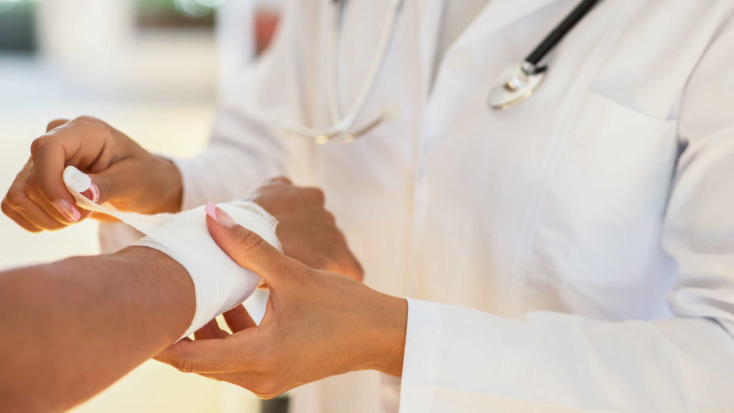 Doctor bandaging a wound on a woman’s forearm