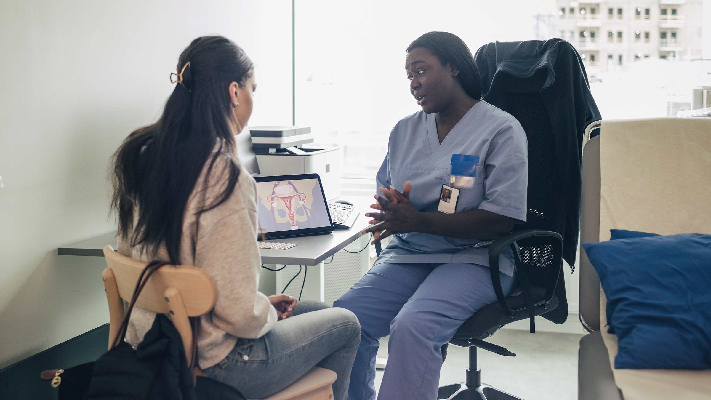 A female doctor conversing with a teenage girl in a clinical setting